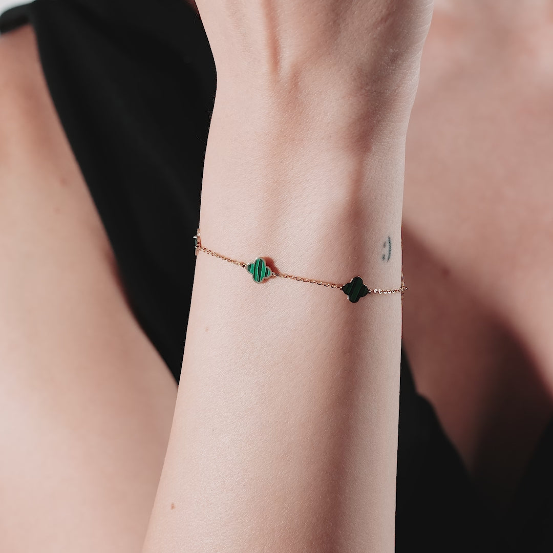 Elegant 14K yellow gold malachite four leaf clover bracelet worn on wrist, showcasing green stone accents and a delicate chain.