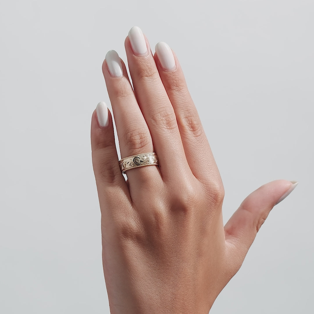 14K yellow gold hand engraved mens wedding band featured on a model's hand with a shiny finish and leaf motif.