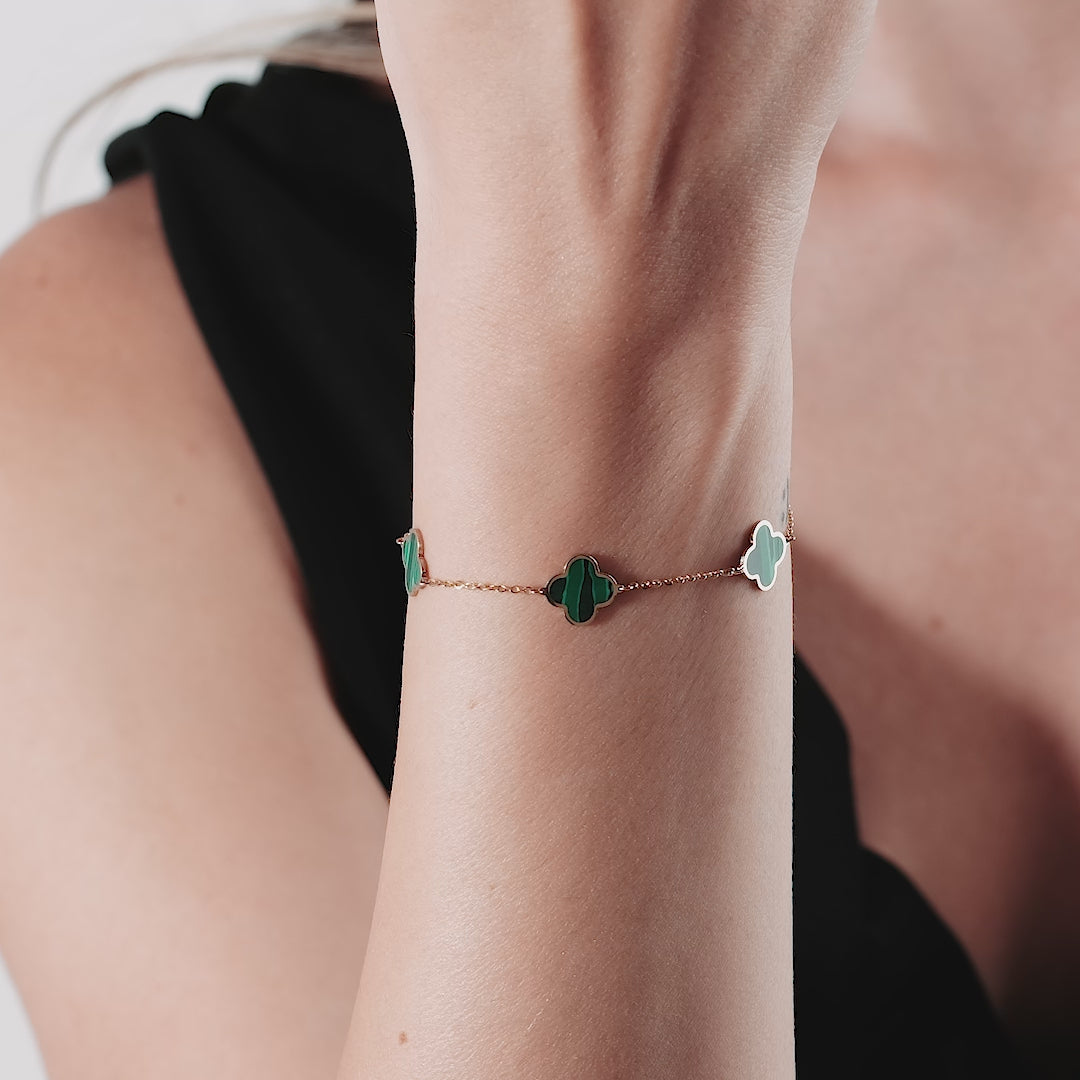 14K yellow gold bracelet featuring four leaf clovers in malachite, elegantly worn on a wrist.