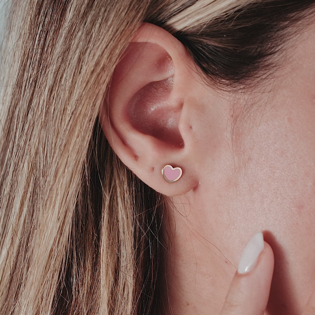 14K yellow gold minimalist pink heart stud earrings worn on ear, showcasing delicate design and everyday elegance.