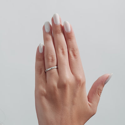 Hand with manicured nails wearing a 3mm white gold dome milgrain wedding band, showcasing a shiny finish.