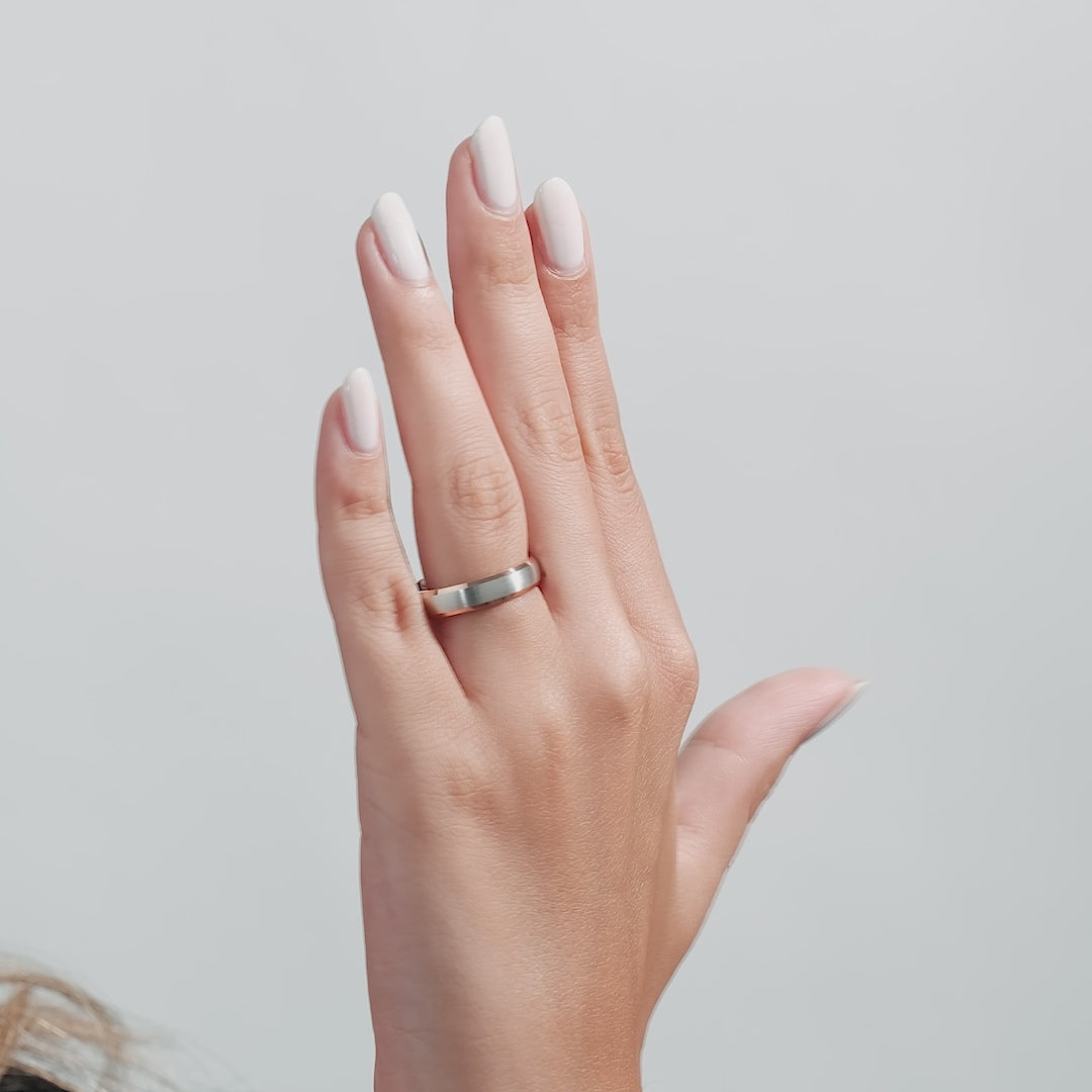 14K white and rose gold men's wedding band worn on a hand with manicured nails, showcasing its unique design.
