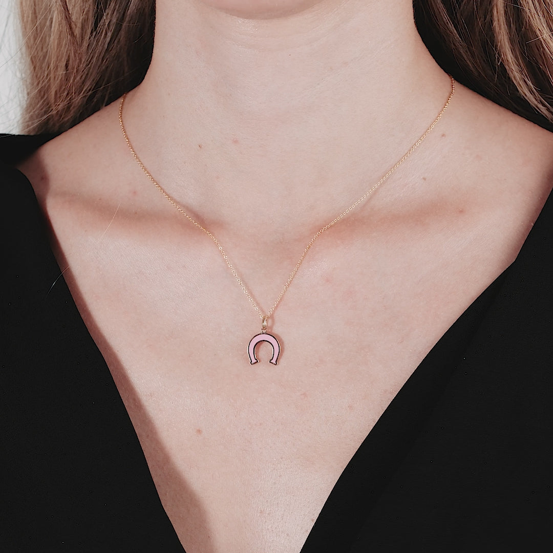 Model wearing a 14K yellow gold dainty pink horseshoe necklace, showcasing a delicate design perfect for everyday use.