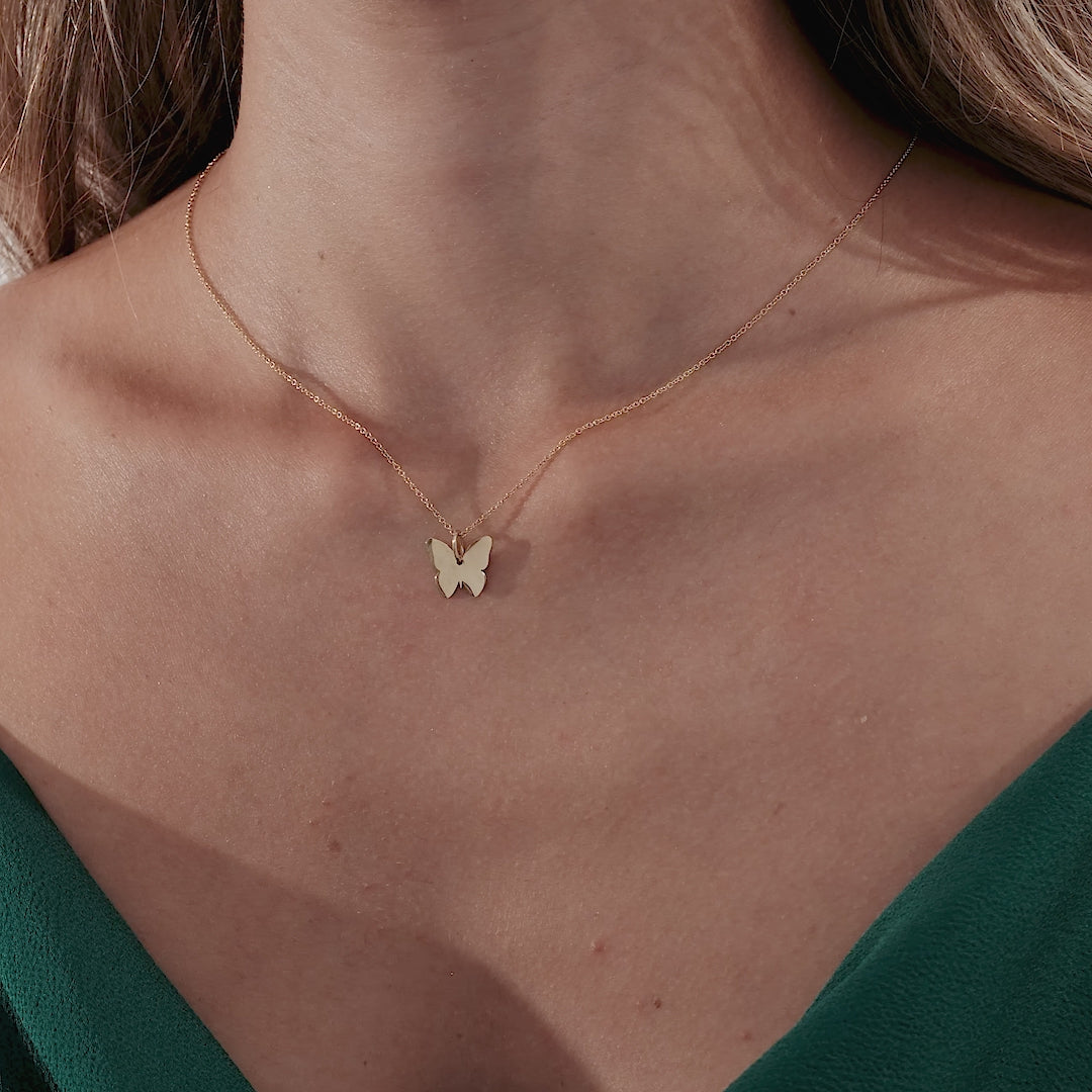Dainty 14K solid yellow gold butterfly necklace worn elegantly on a woman, showcasing its minimalist design.