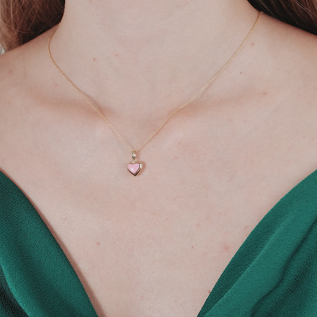 14K yellow gold necklace featuring a pink puffed heart pendant, worn by a model in a green top.