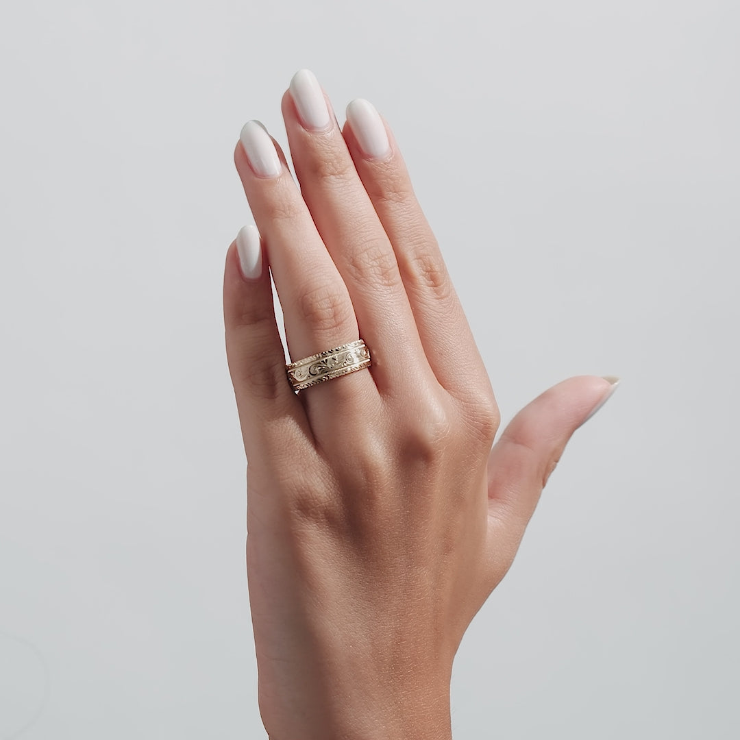 7mm yellow gold hand engraved mens wedding band shown on a hand with soft manicure, featuring a shiny leaf motif.