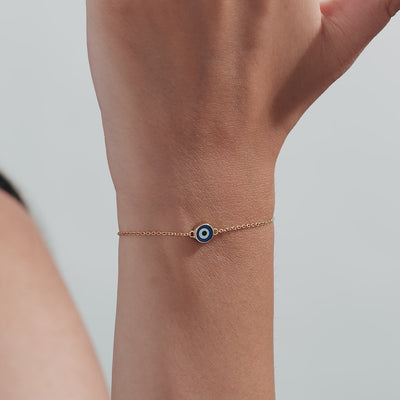 14K solid yellow gold bracelet featuring a blue round evil eye charm on a delicate chain.