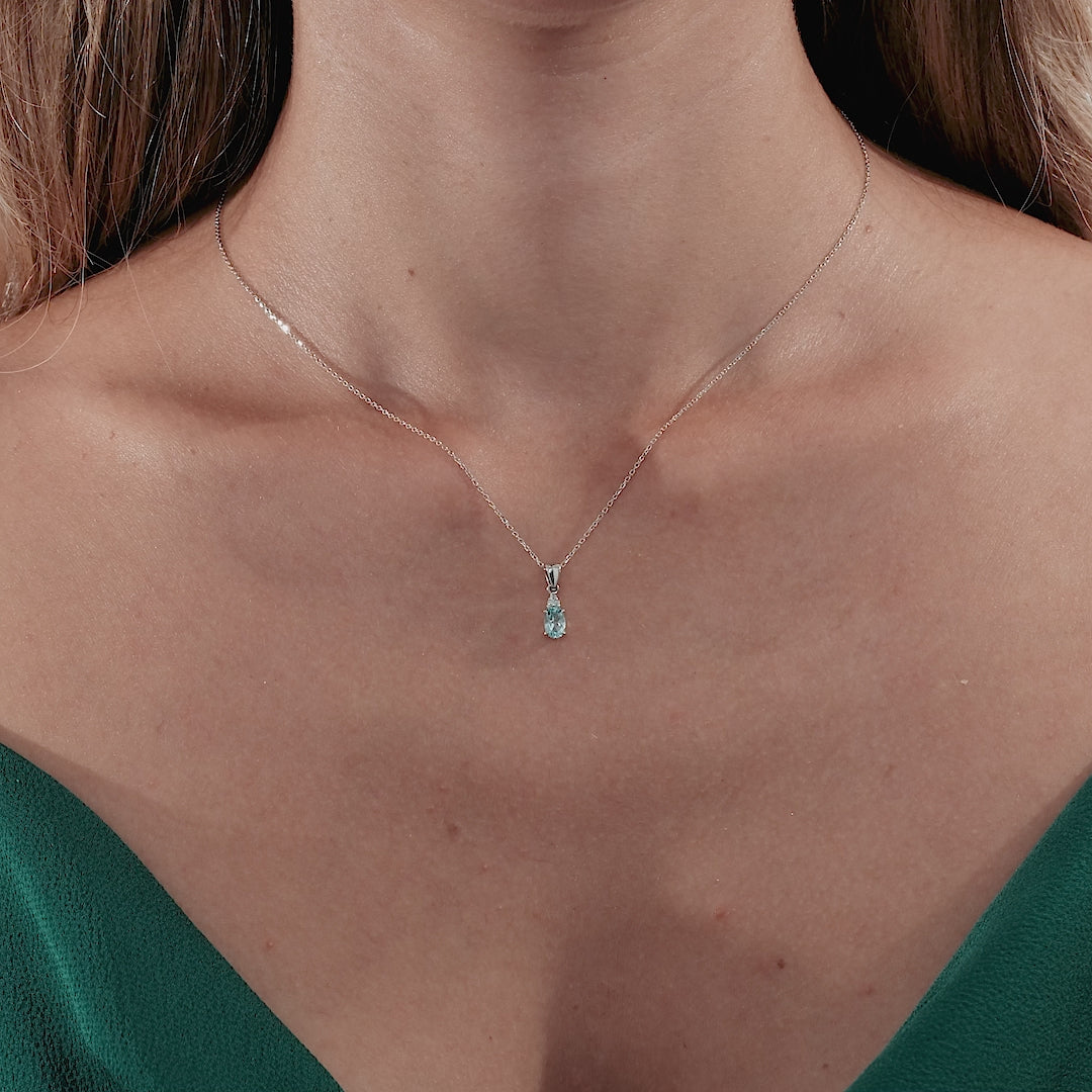 14K yellow gold diamond and blue topaz solitaire necklace worn by a model, showcasing its elegance and daintiness.