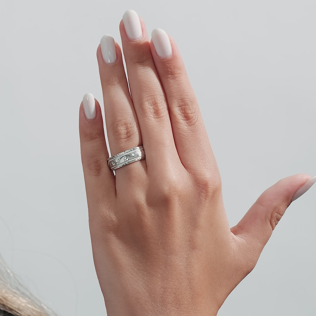 Hand wearing a 7mm hand engraved white gold wedding band with leaf motifs and milgrain details.