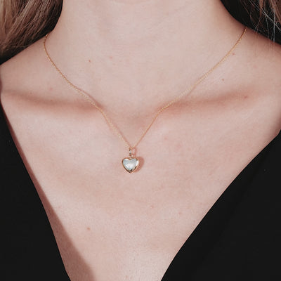 14K yellow gold mother of pearl heart necklace worn elegantly, featuring a dainty puffed heart pendant.