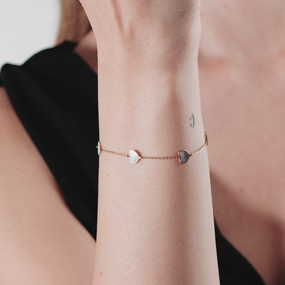 14K yellow gold station bracelet with mother of pearl hearts worn on wrist, elegant and simple design.