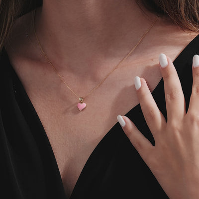 Model wearing a 14K Yellow Gold Pink Enamel Heart Necklace, showcasing a delicate design and elegant look.