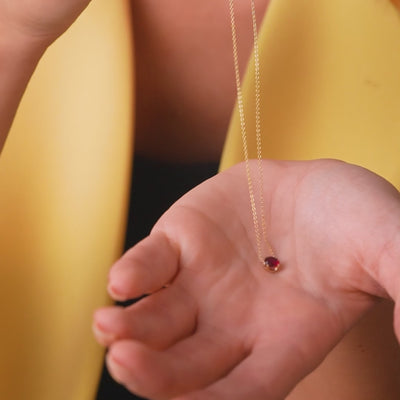 14k yellow gold pear shape ruby necklace held in hand, showcasing its simplicity and elegance.
