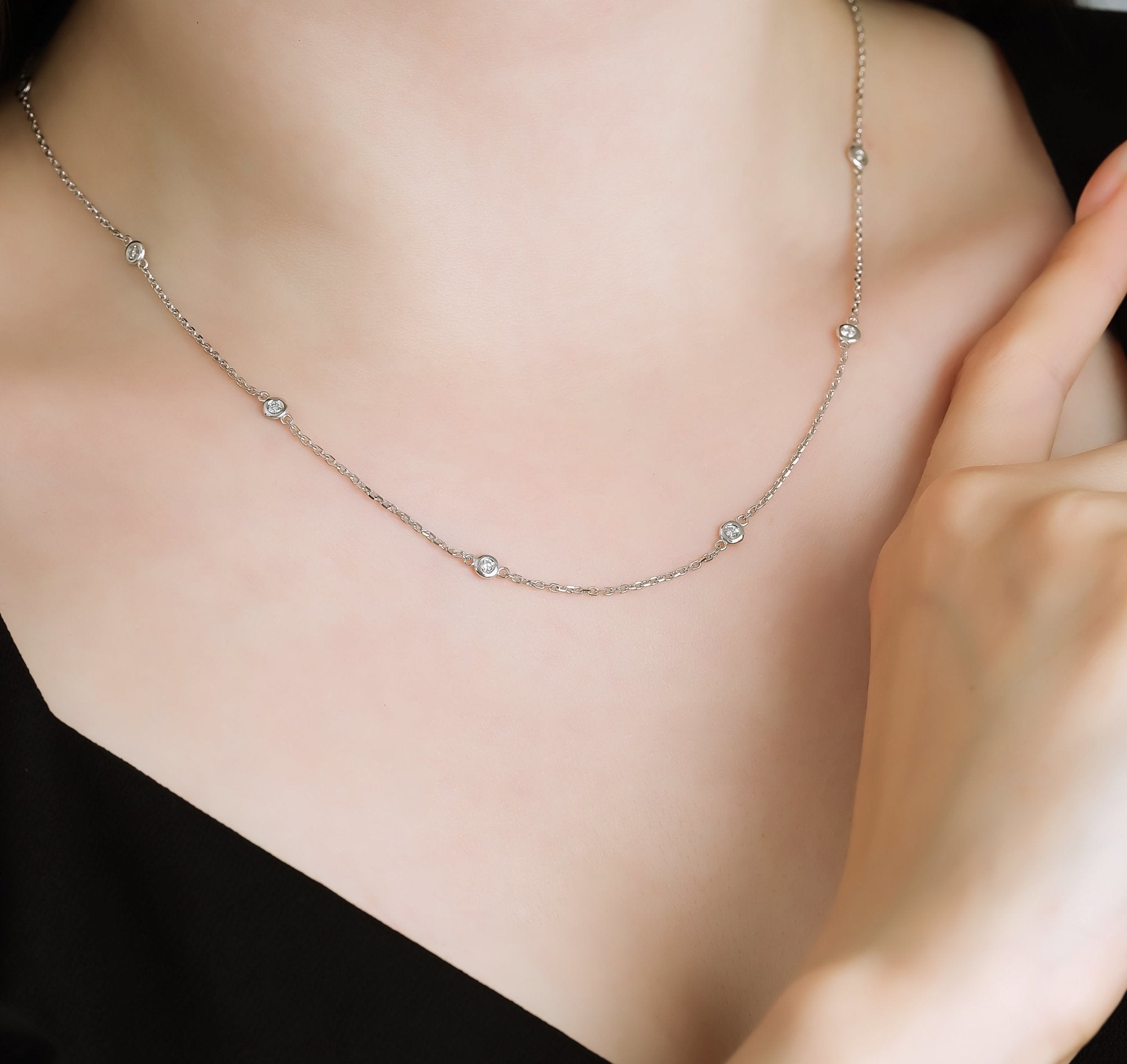 Dainty 14K gold diamond station necklace with bezel set diamonds for everyday elegance, showcased on a model.