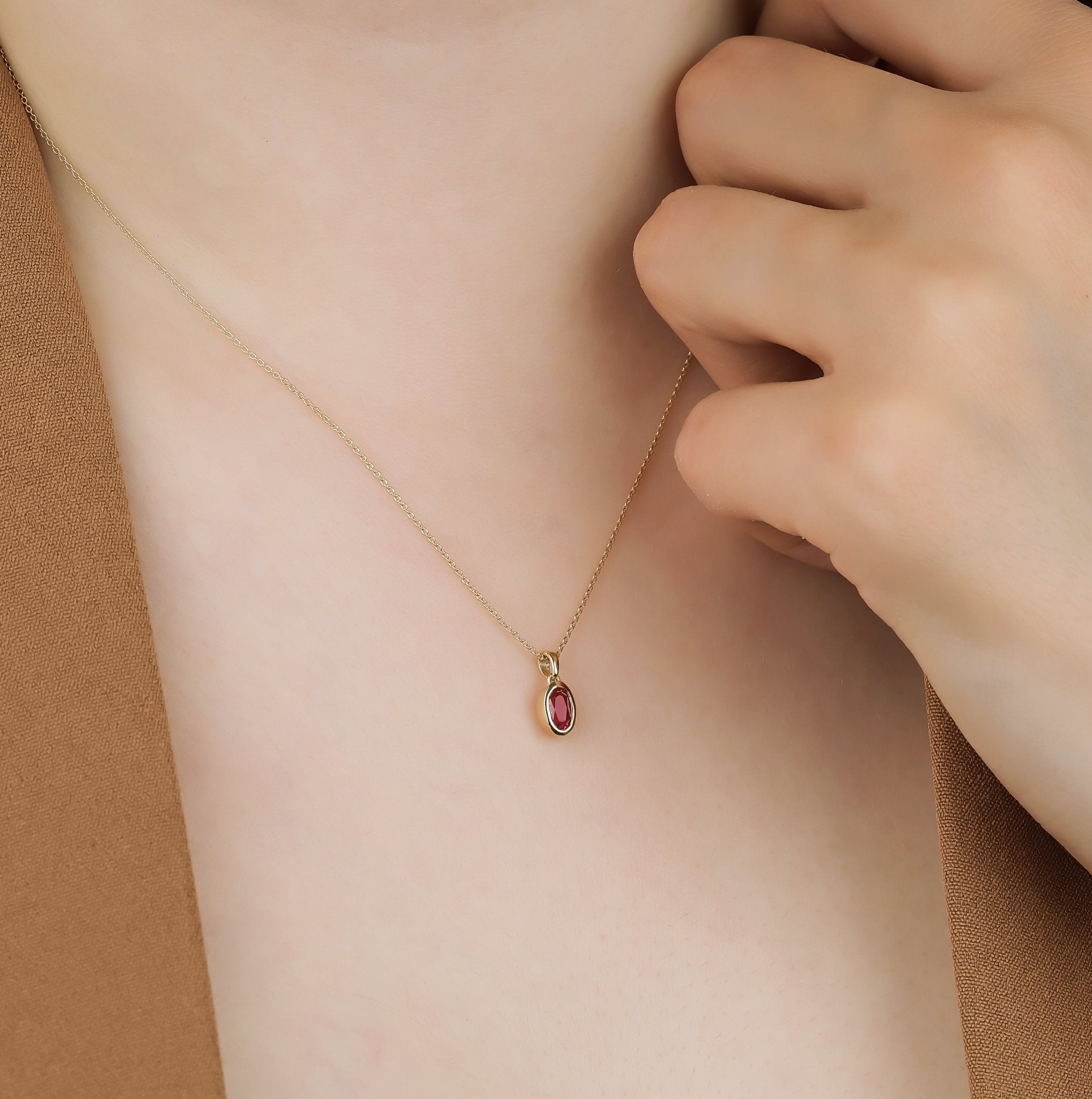 14K gold solitaire ruby necklace worn on a neck, featuring a delicate minimalist design.