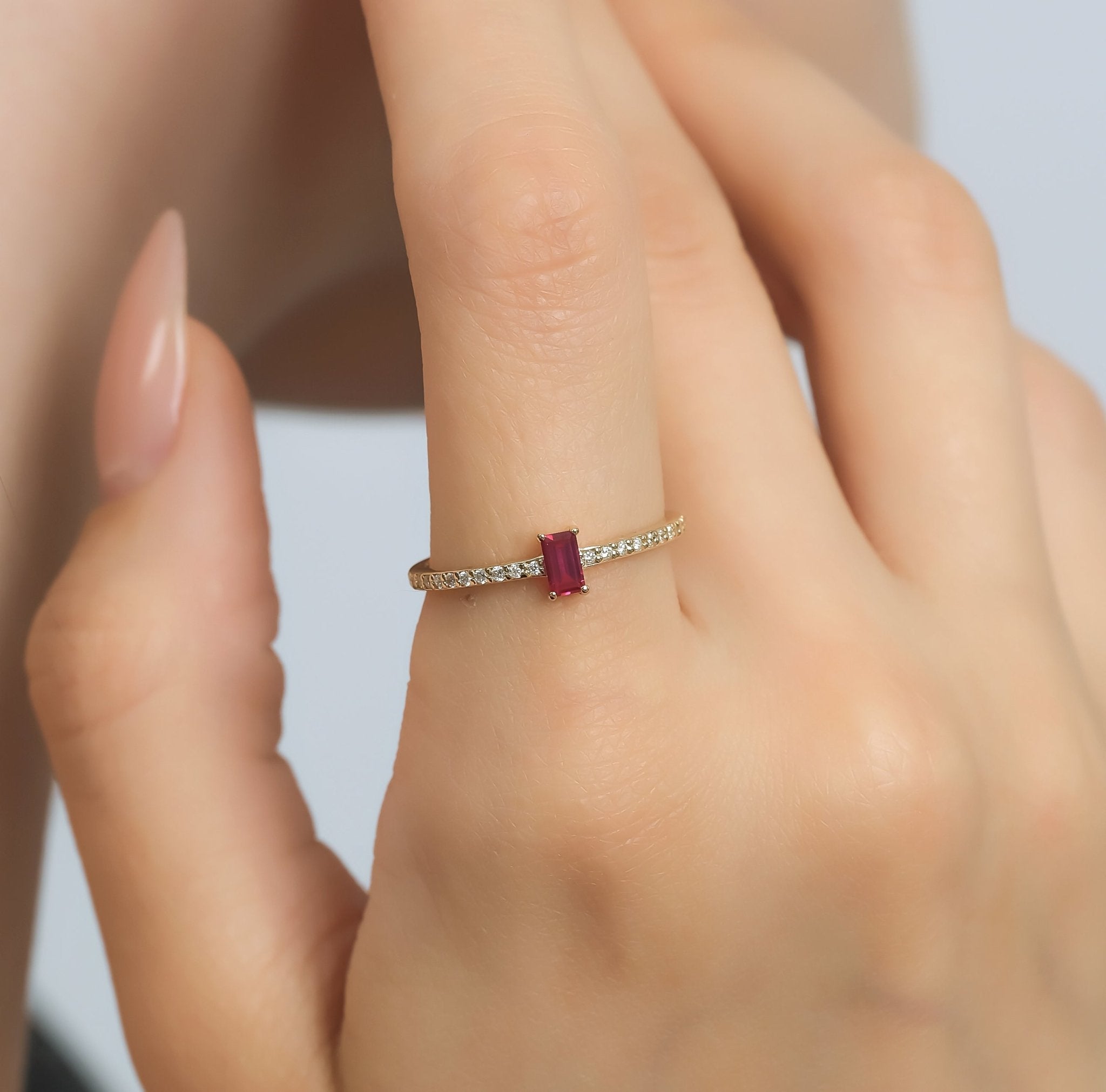 14K gold ruby and diamond eternity wedding ring on finger, showcasing minimalist design and elegant elegance.