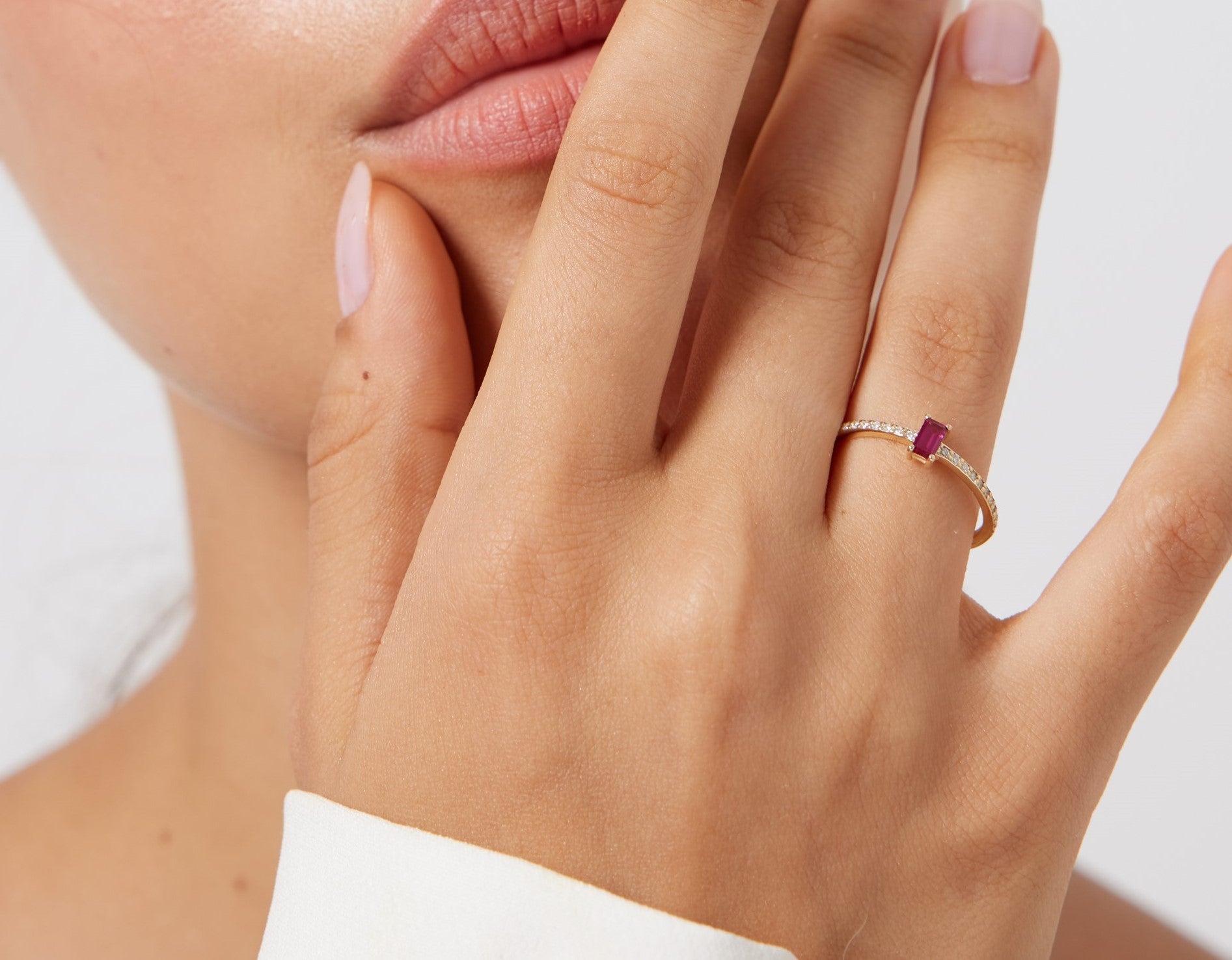 14K gold minimalist eternity wedding ring with ruby and diamond showcased on a woman's finger.
