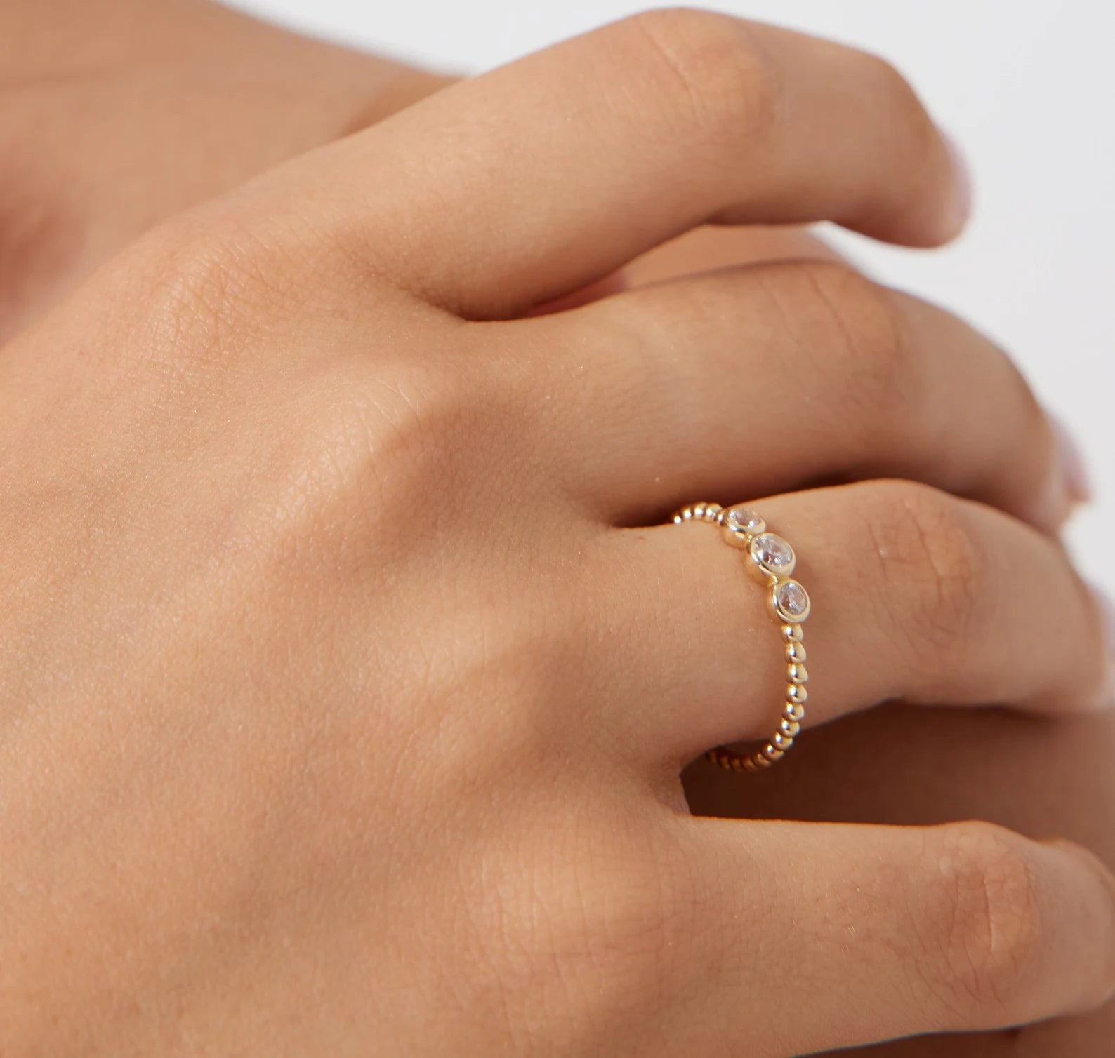 14K gold trio diamond ring worn on a hand, featuring a beaded band and sparkling white diamonds, showcasing luxury jewelry.