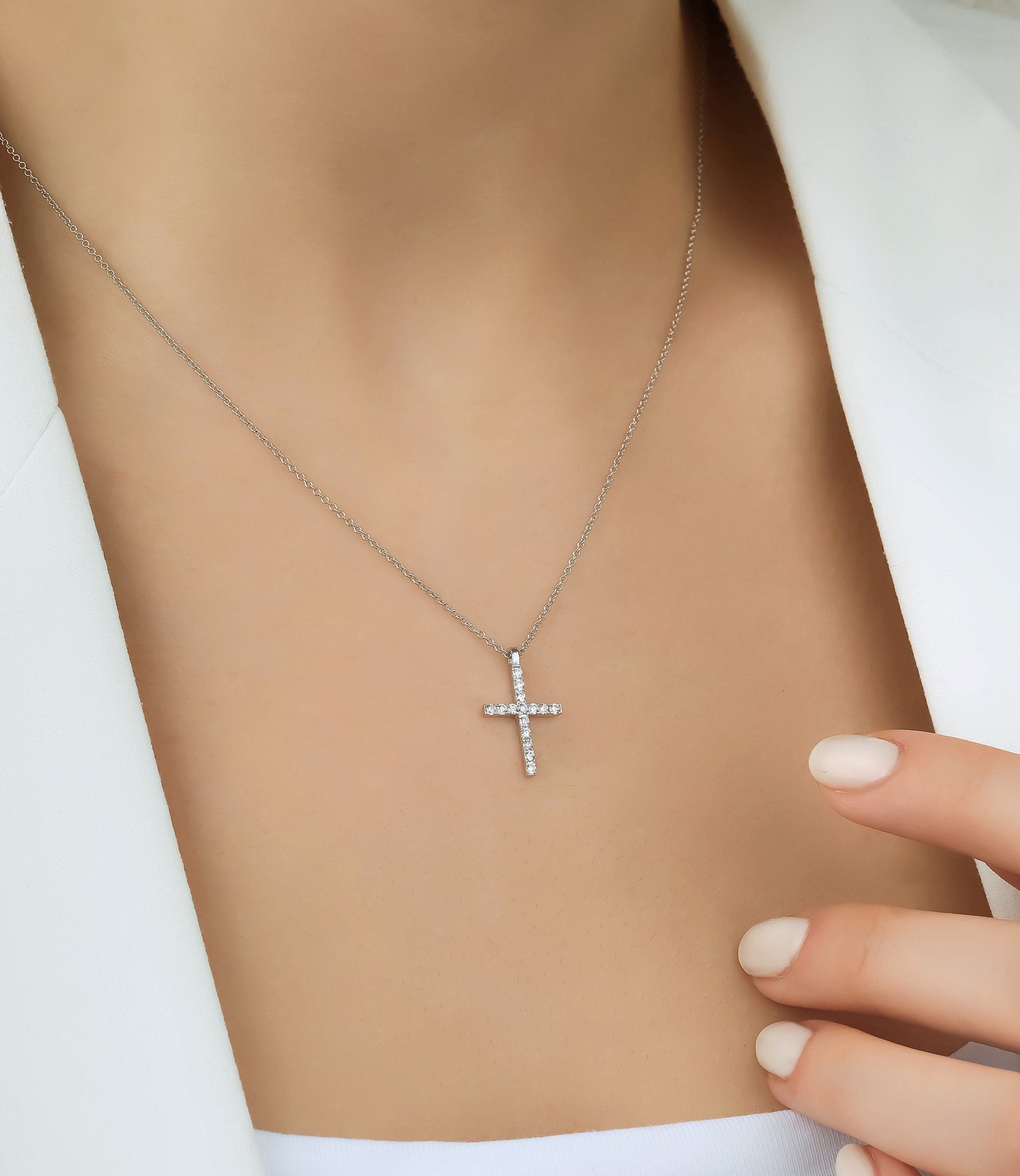 14K solid white gold diamond cross necklace worn by a model, showcasing its delicate design and sparkling diamonds.