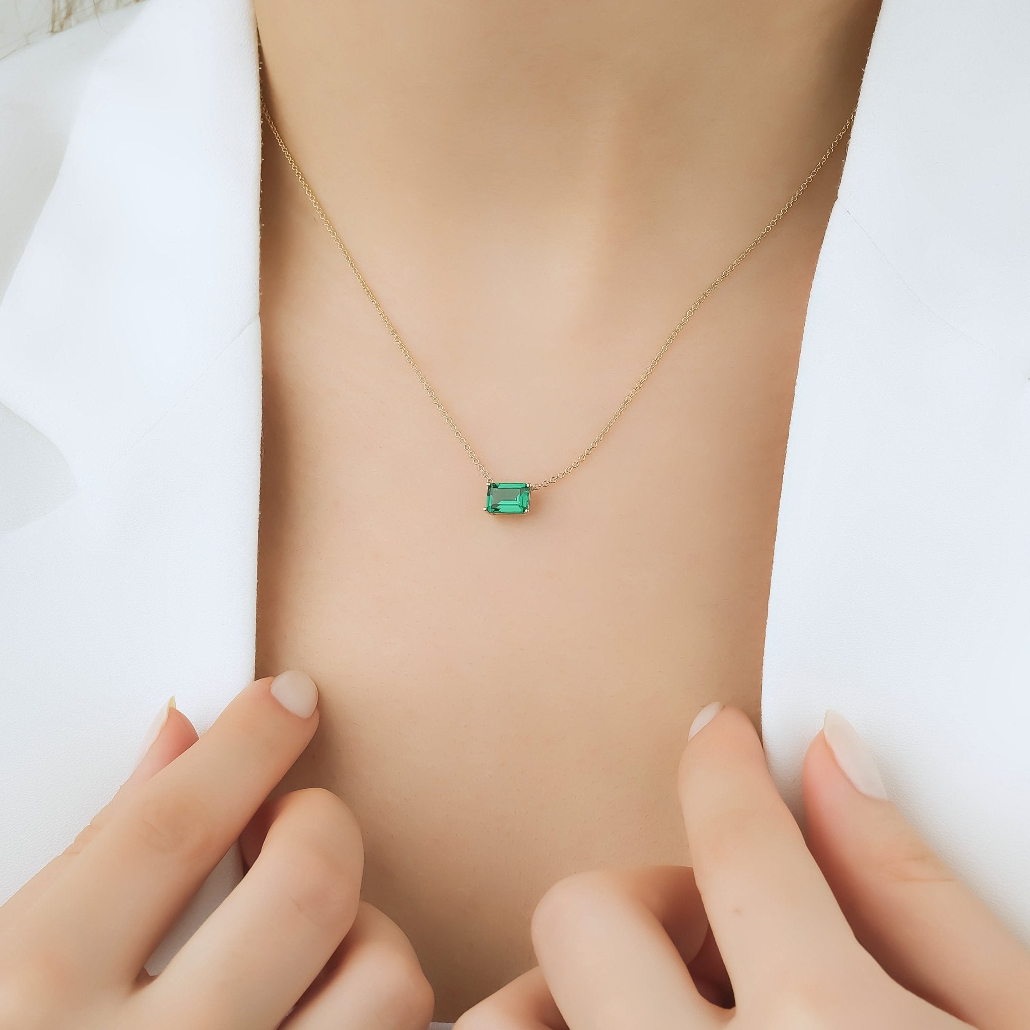 14K solid white gold emerald cut solitaire emerald necklace worn on woman with a minimalist style.