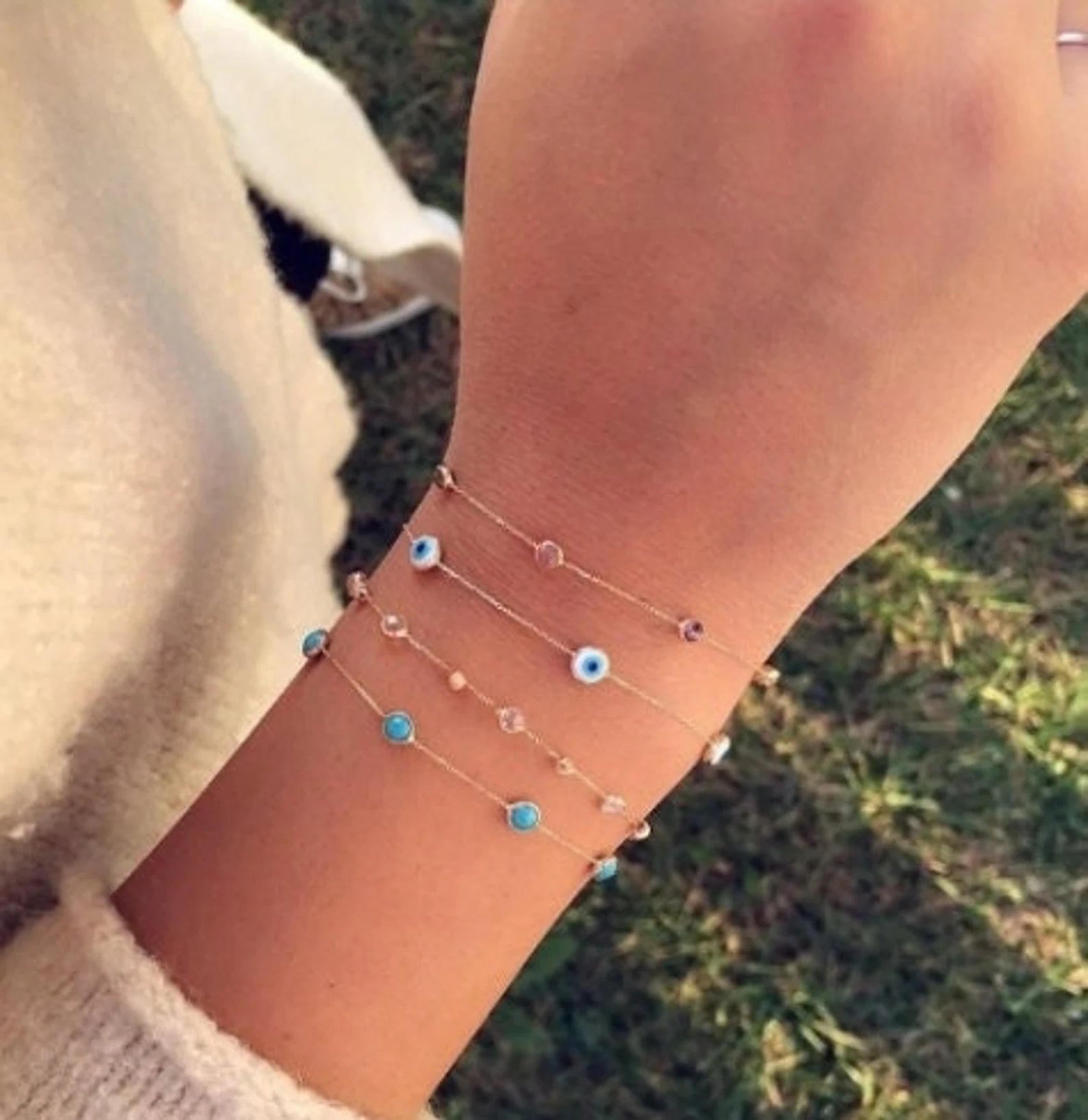 14K solid yellow gold evil eye station bracelet worn on a wrist, showcasing delicate beaded design with multiple evil eye charms.