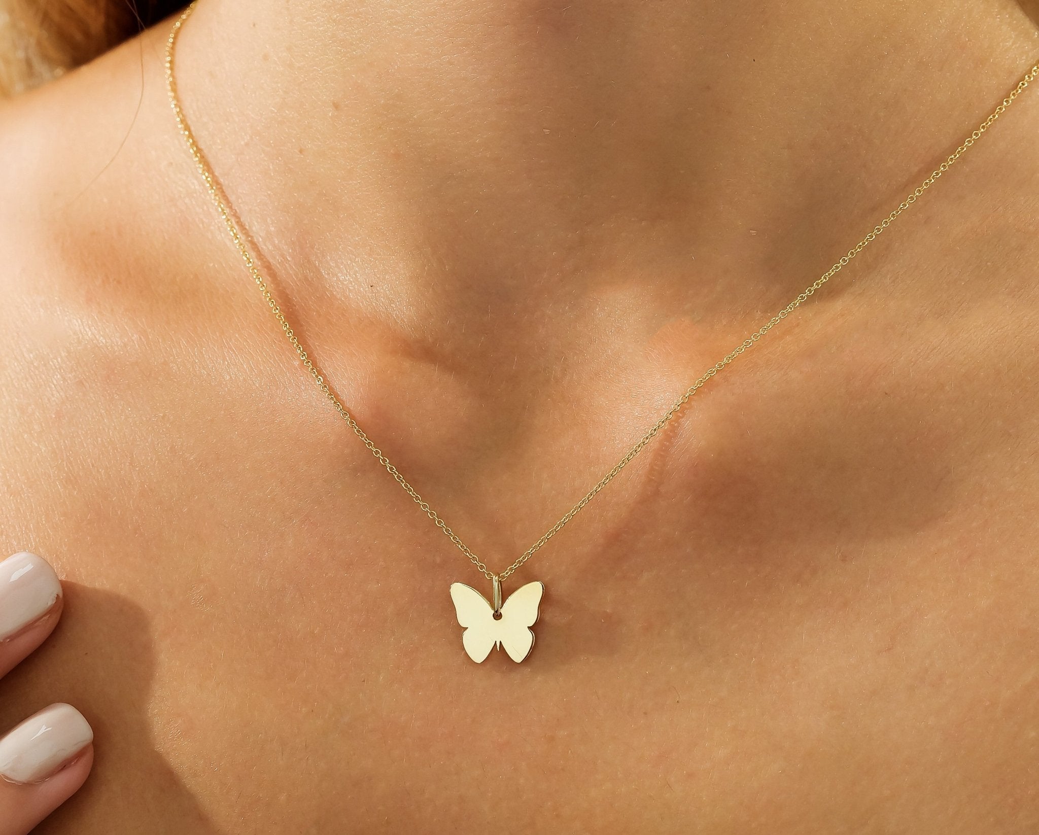 14K solid yellow gold butterfly necklace worn on a woman's neck, showcasing its delicate and minimalist design.
