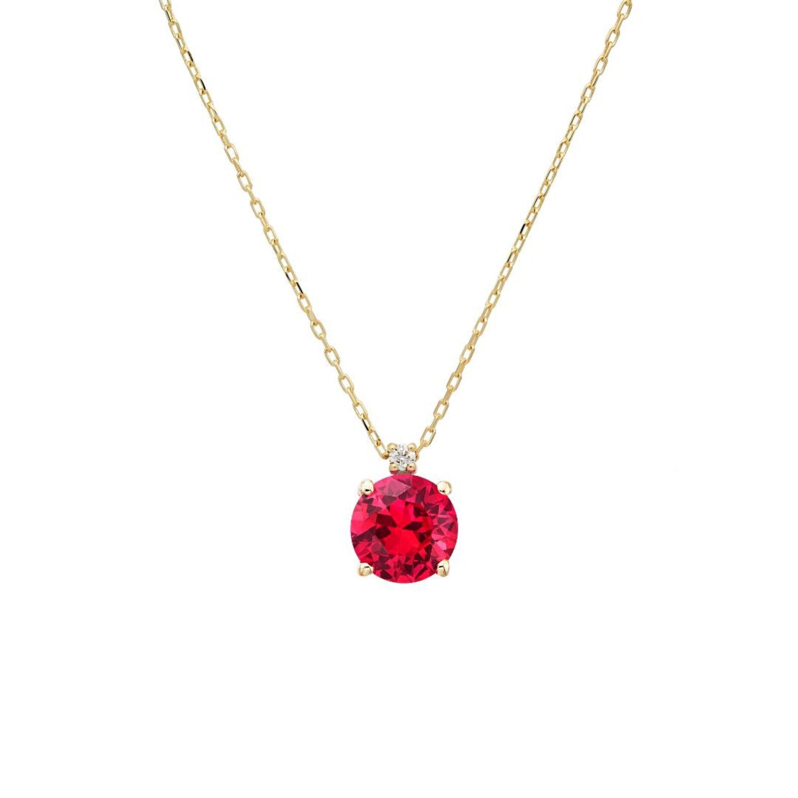 14K yellow gold necklace featuring a round lab-created ruby pendant adorned with a natural diamond.