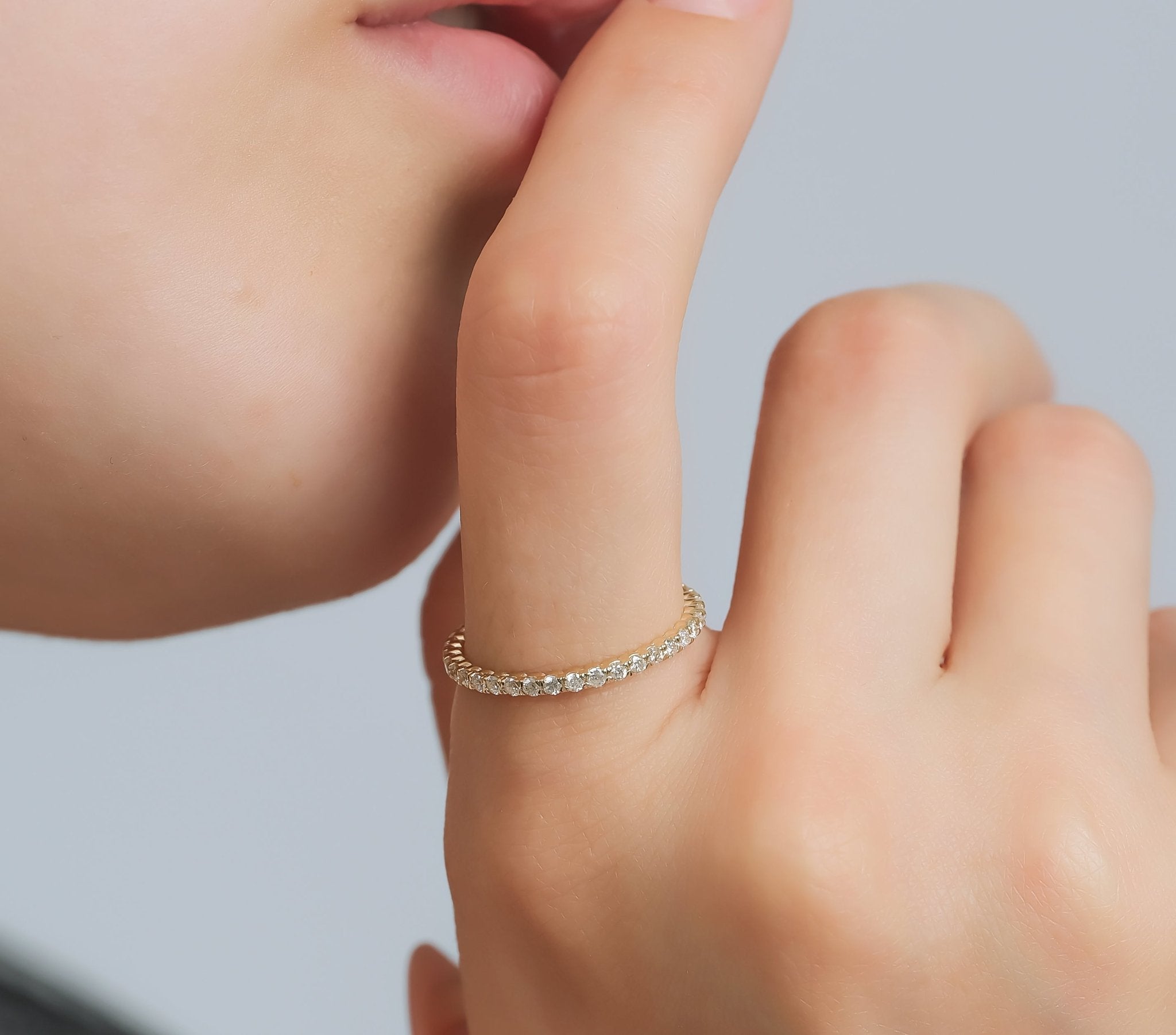 14K gold full eternity diamond wedding ring showcased on a finger, featuring round diamonds and shiny finish.