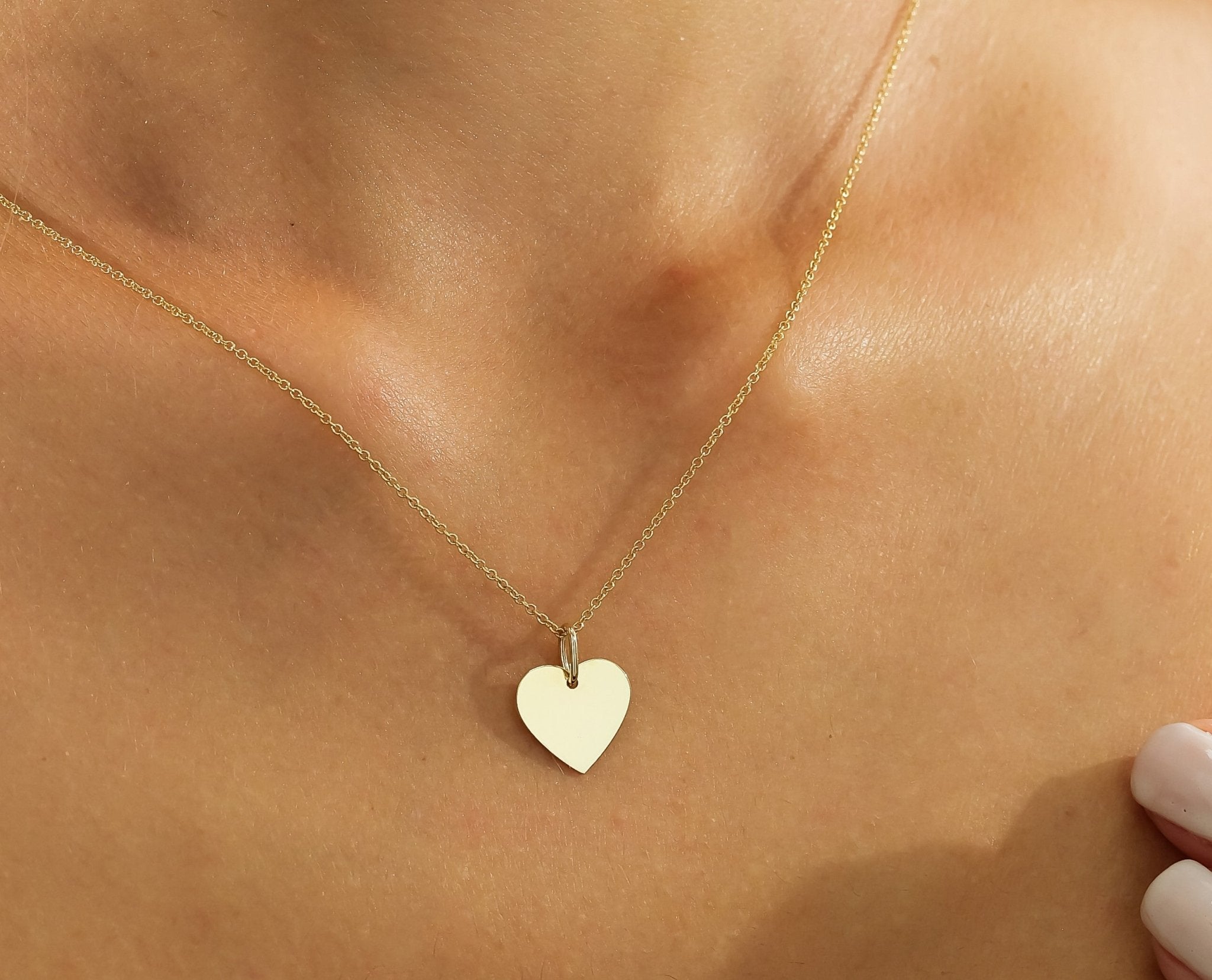 Close-up of a dainty 14K solid yellow gold heart necklace worn on a neck, showcasing its minimalist design.