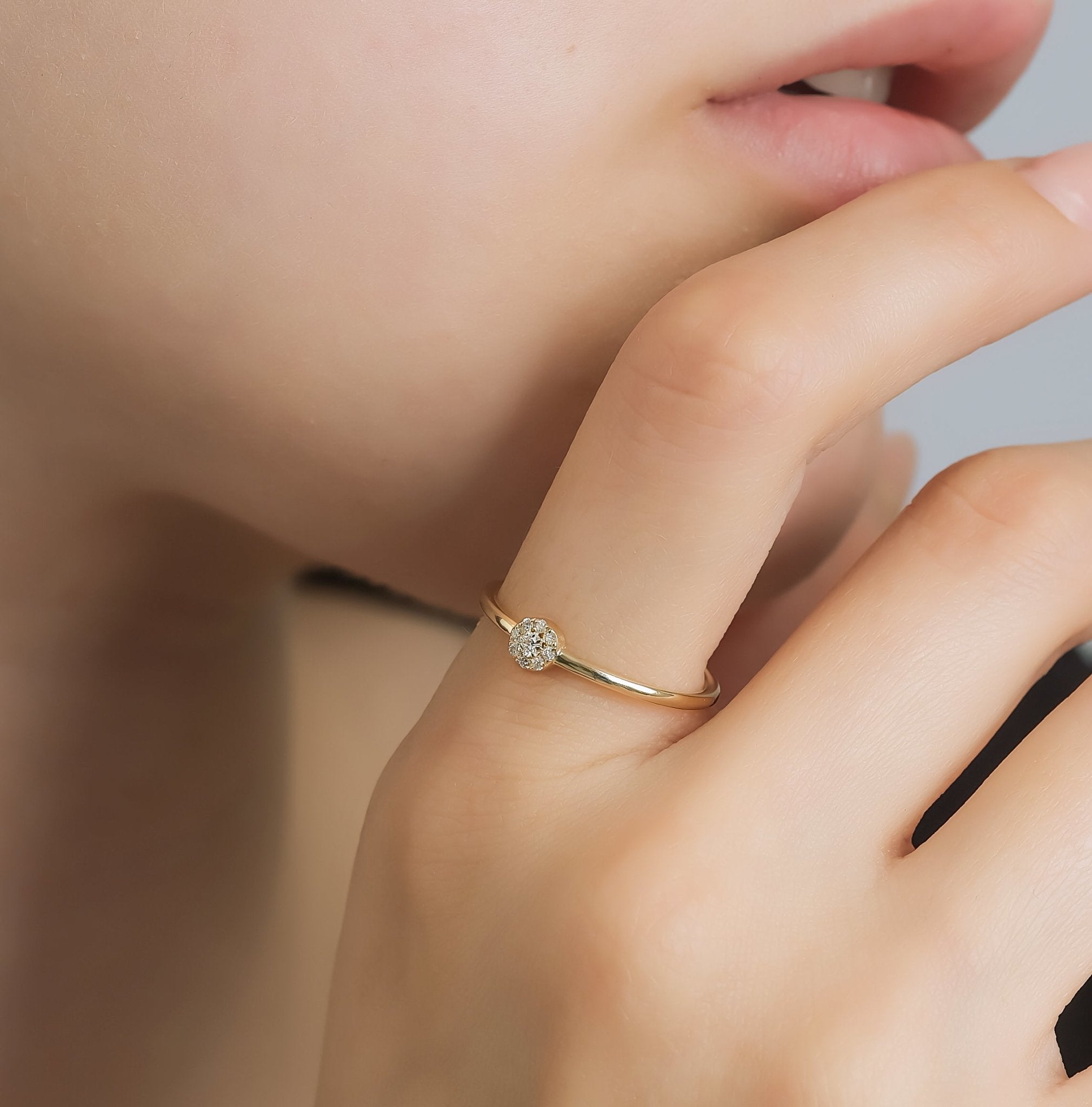 Model wearing a 14K gold minimalist halo diamond ring with round diamonds, showcasing its dainty design and shiny finish.