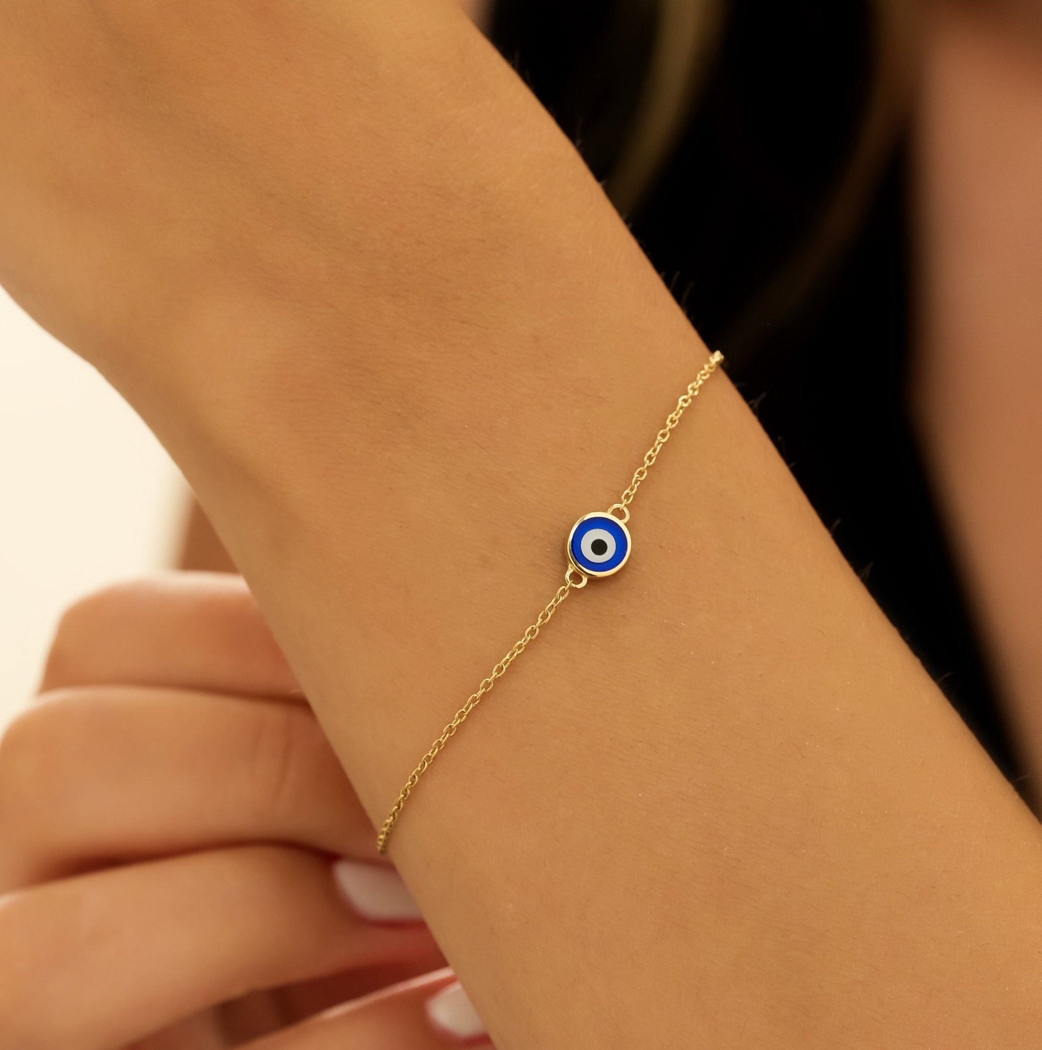 14K solid yellow gold minimalist evil eye bracelet worn on wrist, featuring blue and white eye design, perfect for everyday use.