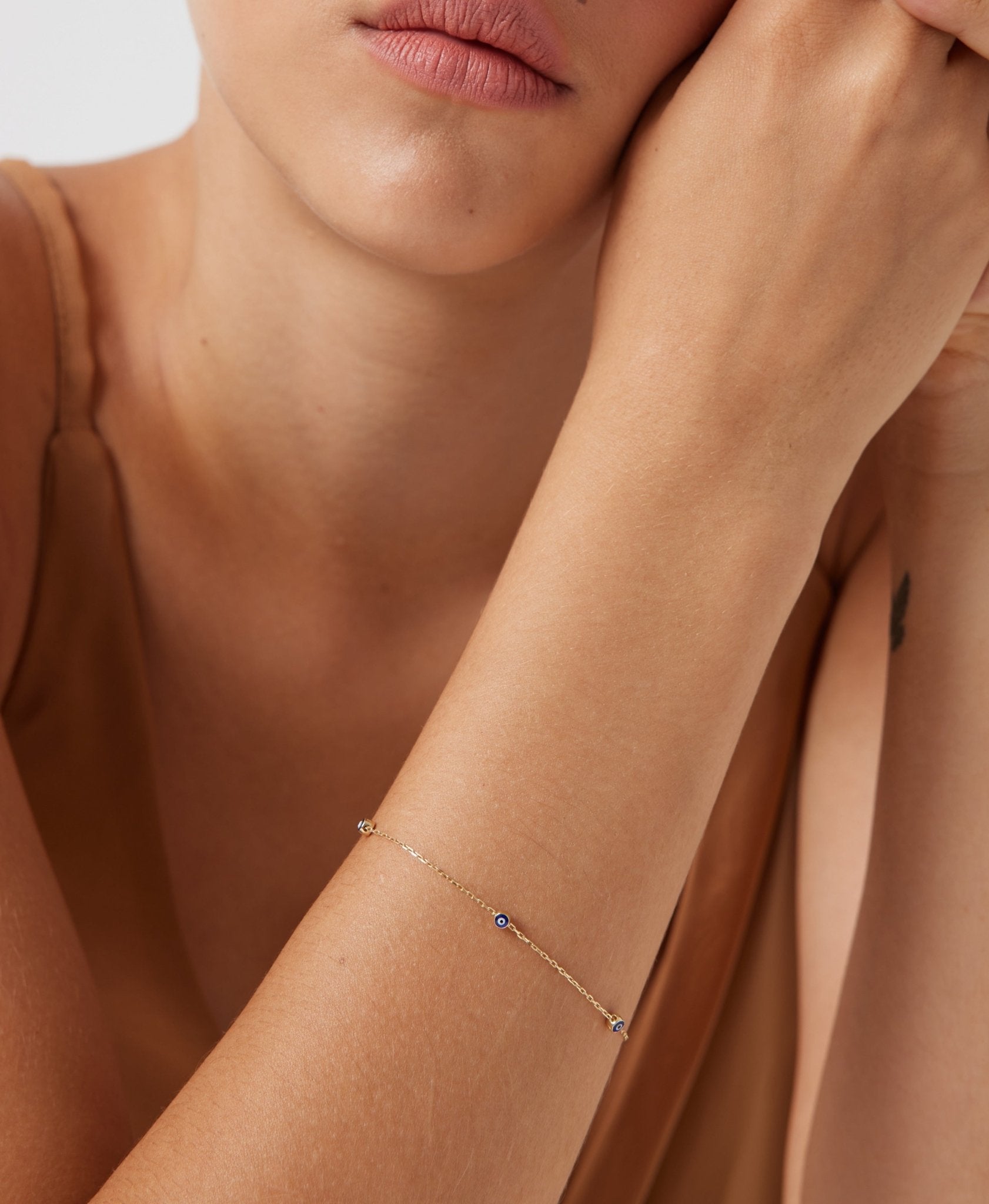 Minimalist 14K solid yellow gold evil eye bracelet showcased on model's wrist.
