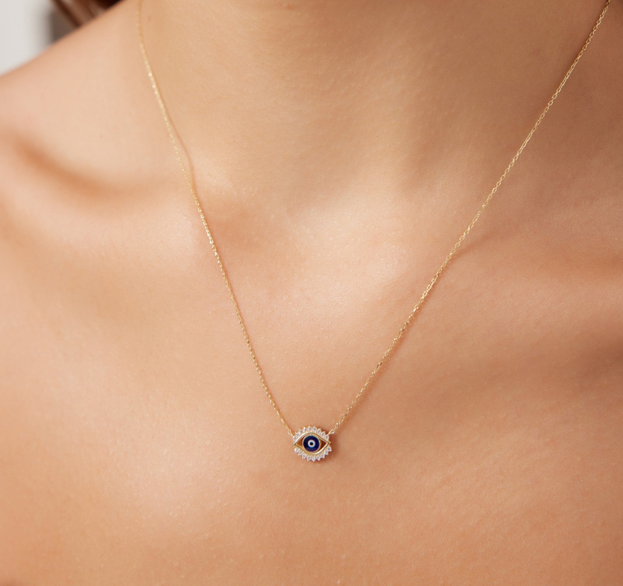 Dainty 14K solid yellow gold minimalist evil eye necklace worn by woman, featuring CZ details, perfect for everyday use.