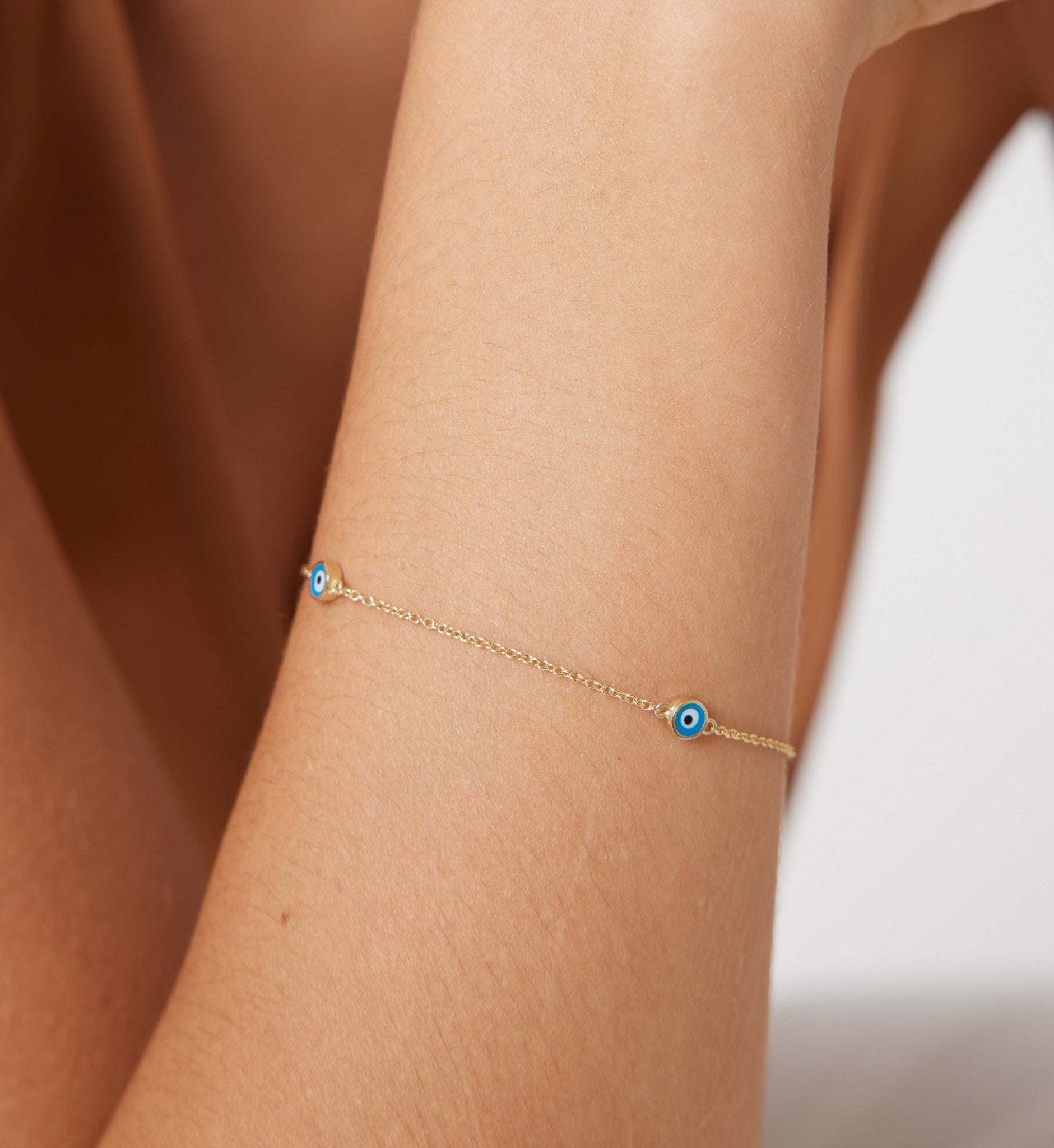 14K solid yellow gold minimalist evil eye bracelet worn on wrist, showcasing dainty design and delicate aesthetic.