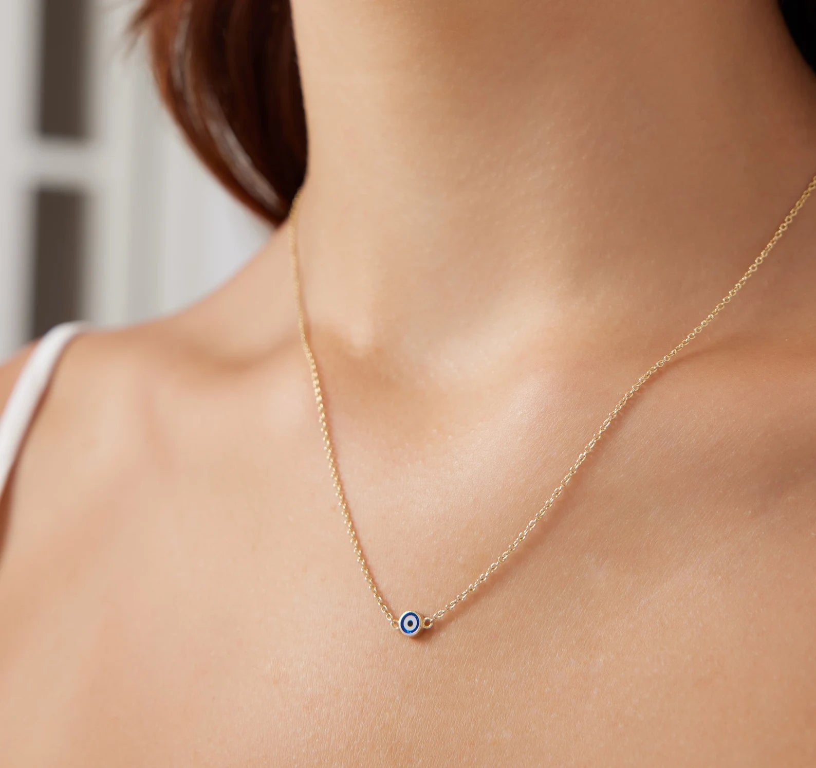 Minimalist 14K solid yellow gold evil eye necklace on a model, showcasing its dainty design and elegant charm.