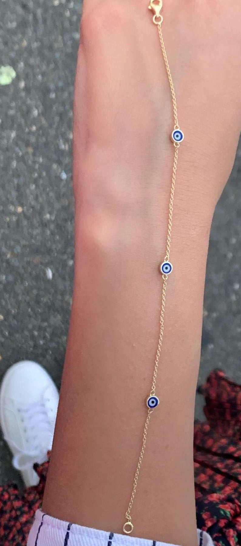 14K solid yellow gold minimalist evil eye bracelet worn on wrist with three blue evil eye charms, perfect for everyday style.