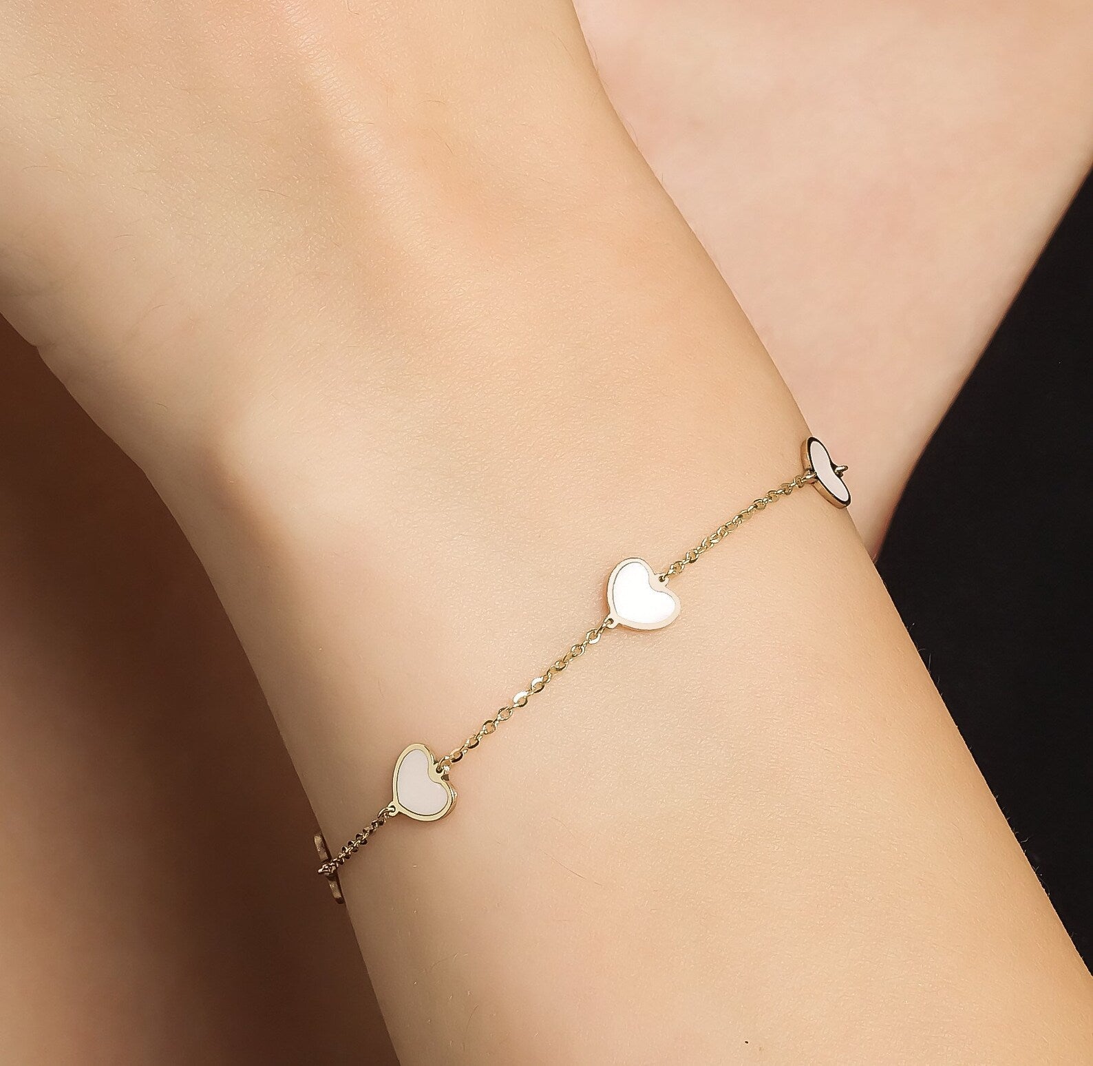 14K solid yellow gold minimalist bracelet with pink hearts, worn on wrist, showcasing elegant design and delicate craftsmanship.
