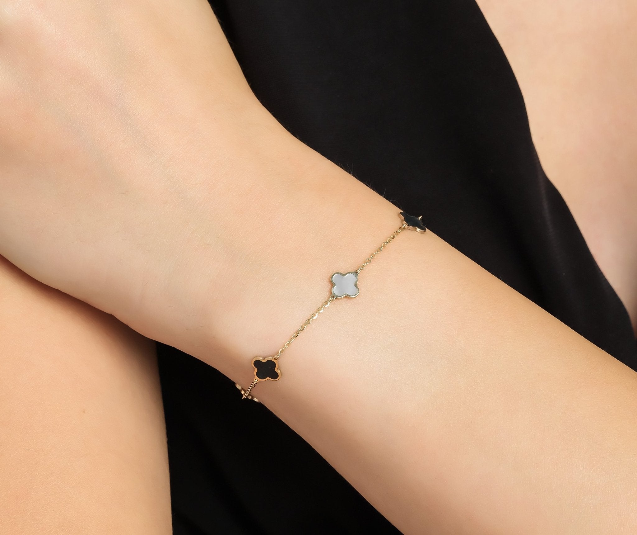 14K solid yellow gold bracelet featuring Mother of Pearl and Onyx four leaf clovers, elegantly worn on a wrist.