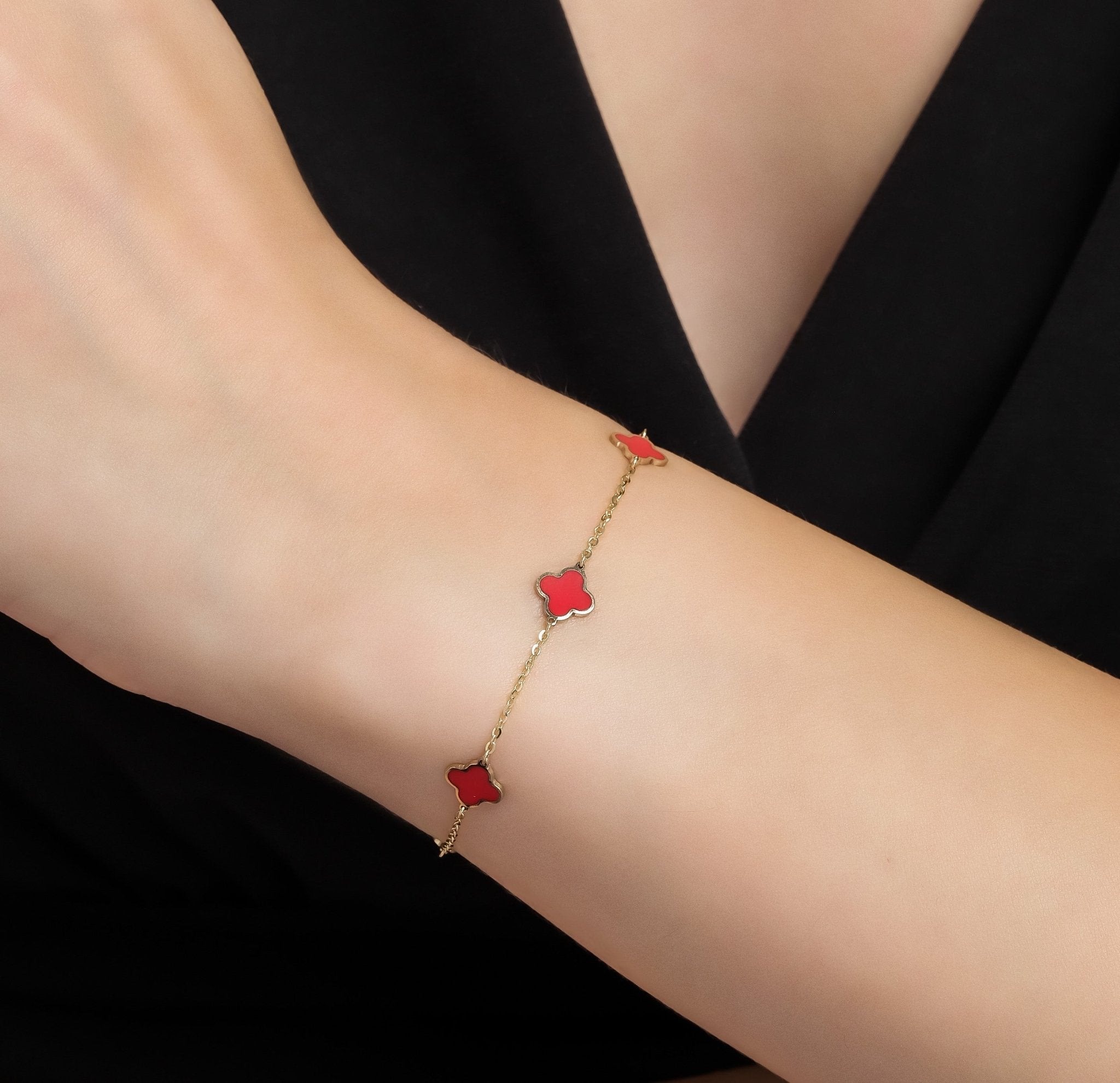 14K solid yellow gold bracelet with red coral four leaf clover design, worn on a delicate wrist, perfect for everyday elegance.