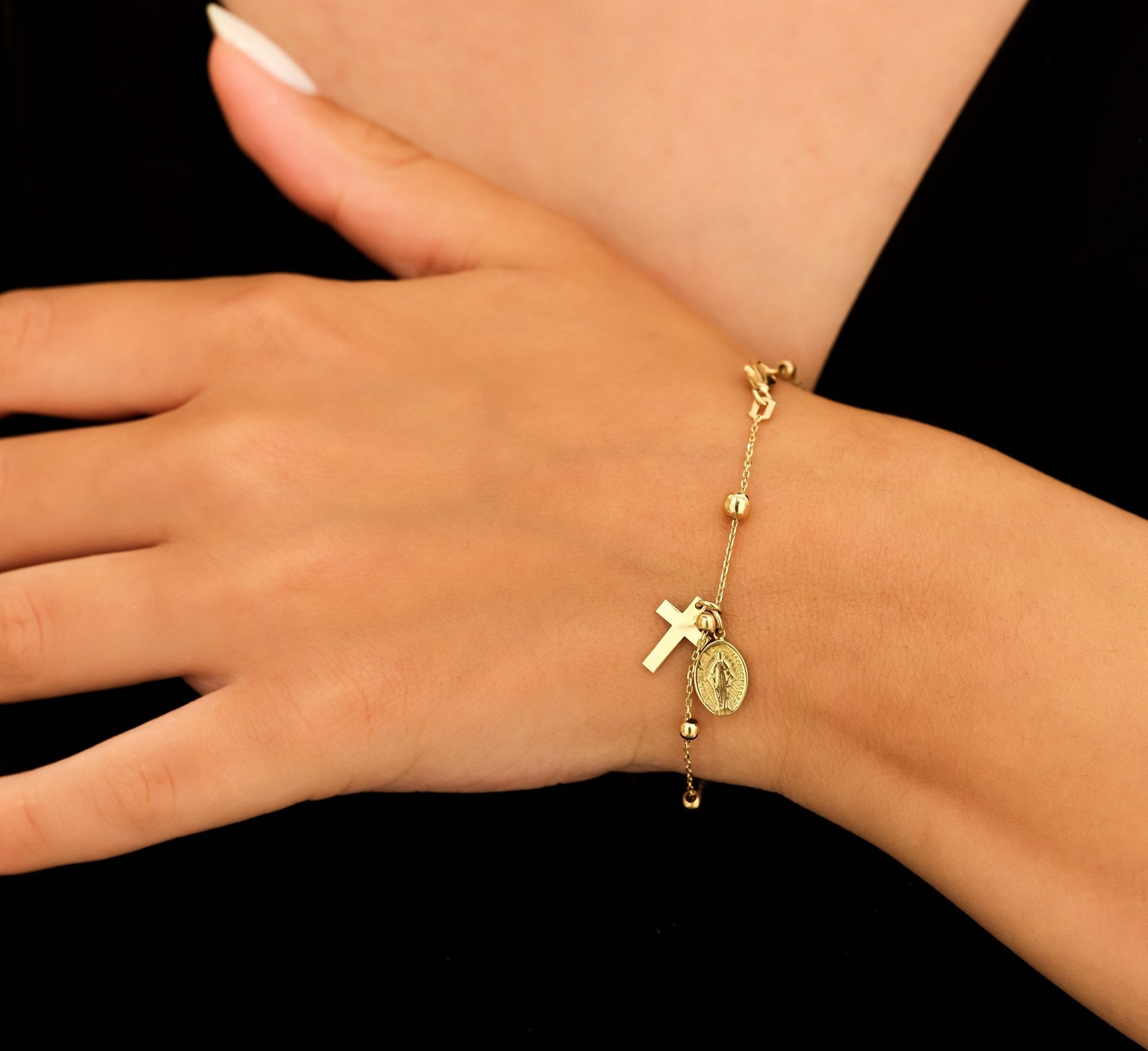 Dainty 14K solid yellow gold rosary bracelet with Virgin Mary and cross charms, worn on a woman's wrist.