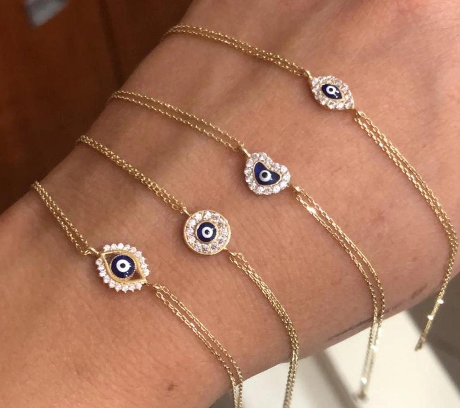 Dainty 14K solid yellow gold round evil eye bracelets with CZ, displayed on a wrist.