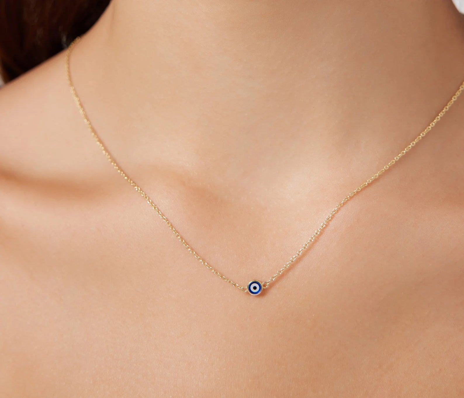 14K solid yellow gold evil eye necklace on model, featuring delicate design and dark blue pendant for everyday elegance.