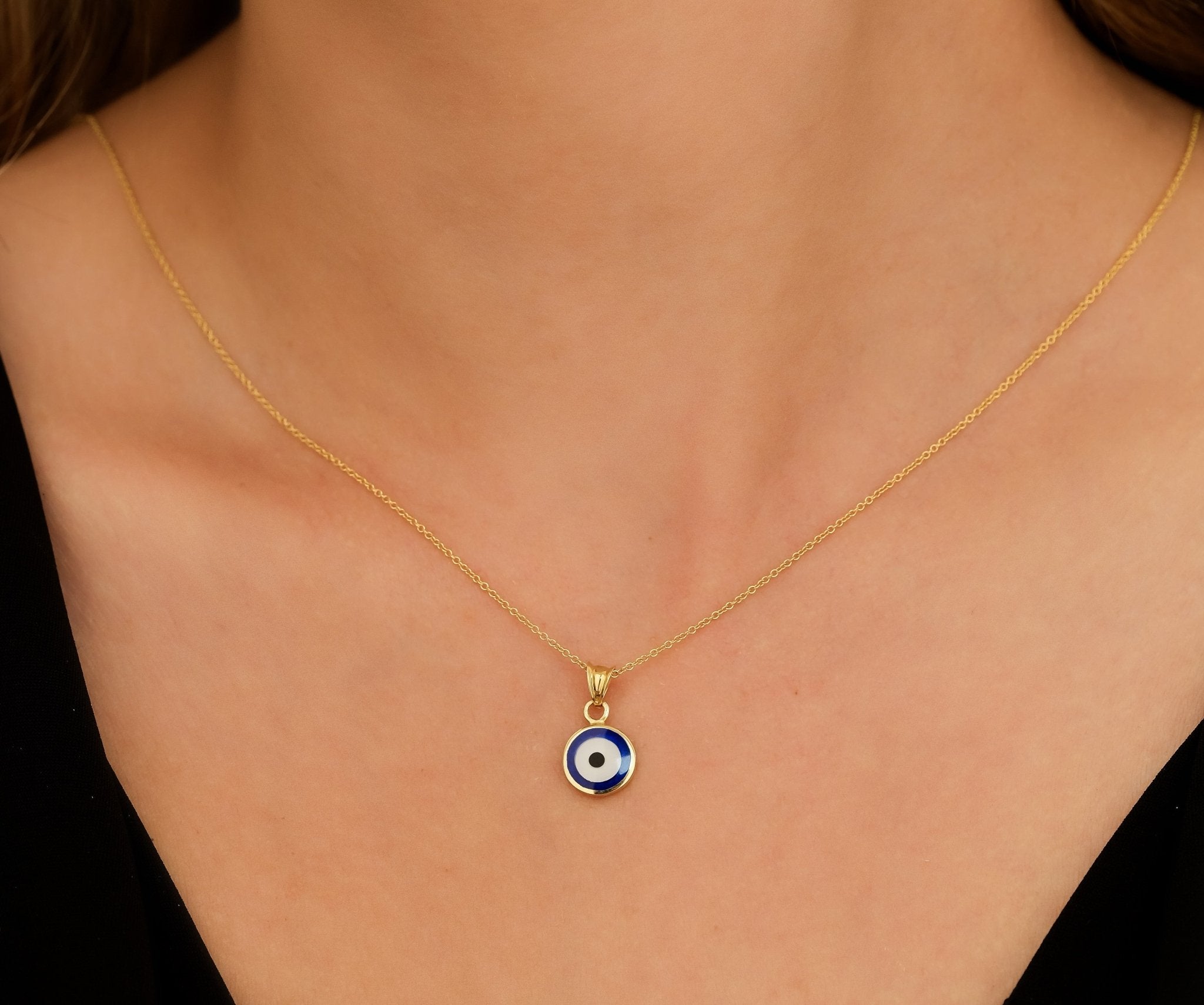 14K solid yellow gold round evil eye pendant necklace worn on a woman's neck, featuring a delicate design.