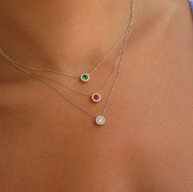 Dainty layered necklace featuring green, red, and clear gems on delicate gold chains, showcasing minimalist jewelry style.