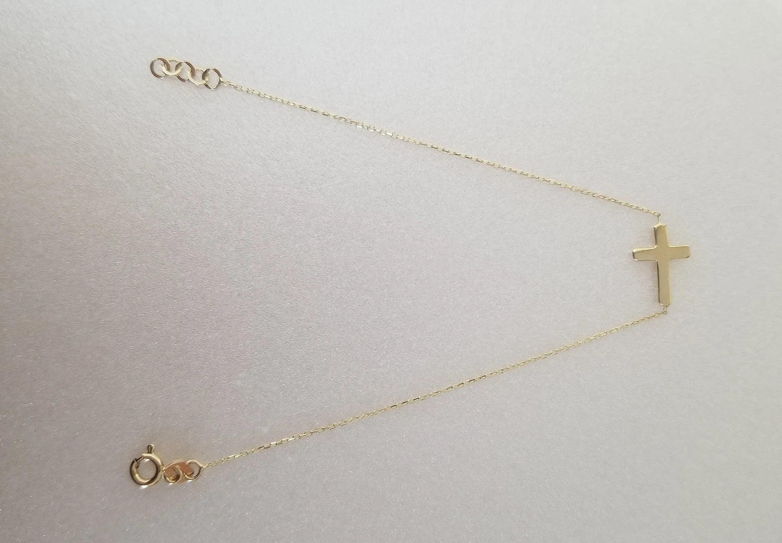 14K solid yellow gold sideway cross bracelet on a light background, featuring a minimalist design perfect for everyday wear.