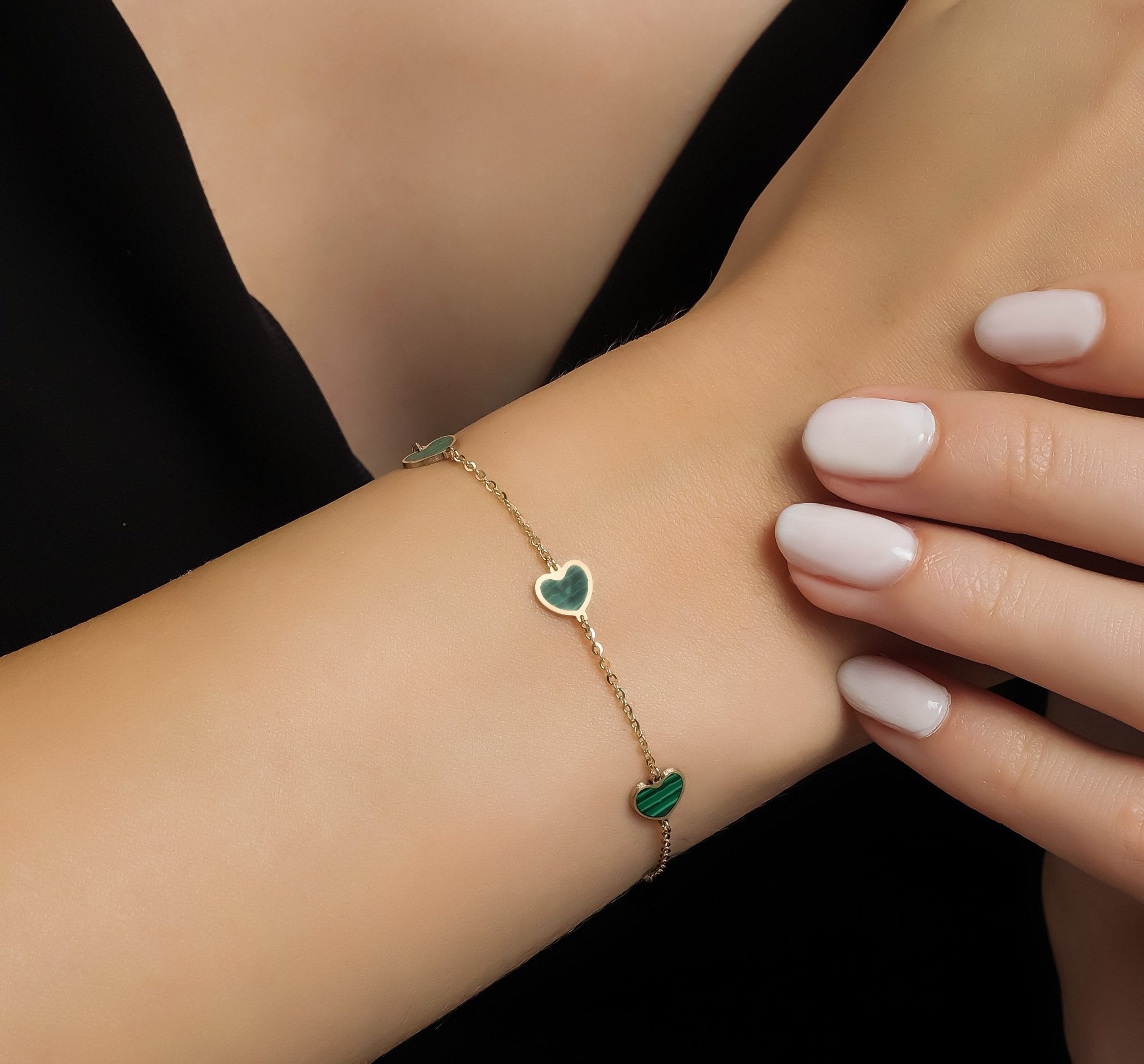 14K solid yellow gold station malachite heart bracelet on a woman's wrist, featuring stunning green heart accents.