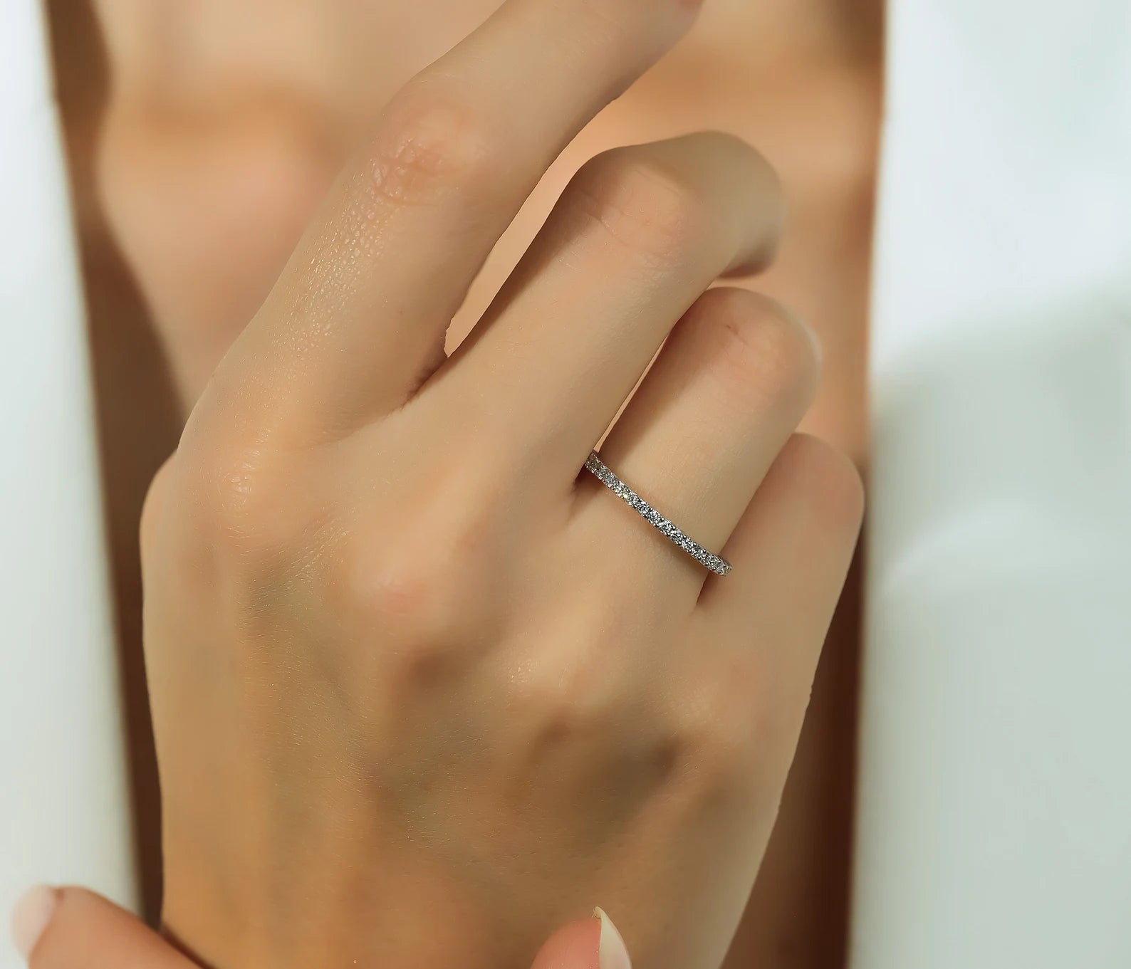 Hand wearing a 14K white gold diamond eternity ring with 0.60 carats, showcasing sparkling diamonds and elegant design.