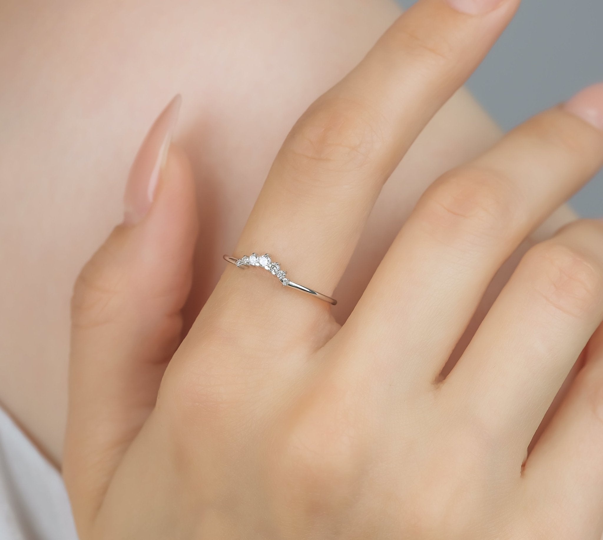 14K white gold curved diamond wedding ring on a woman's hand featuring 7 round diamonds, minimalistic design.