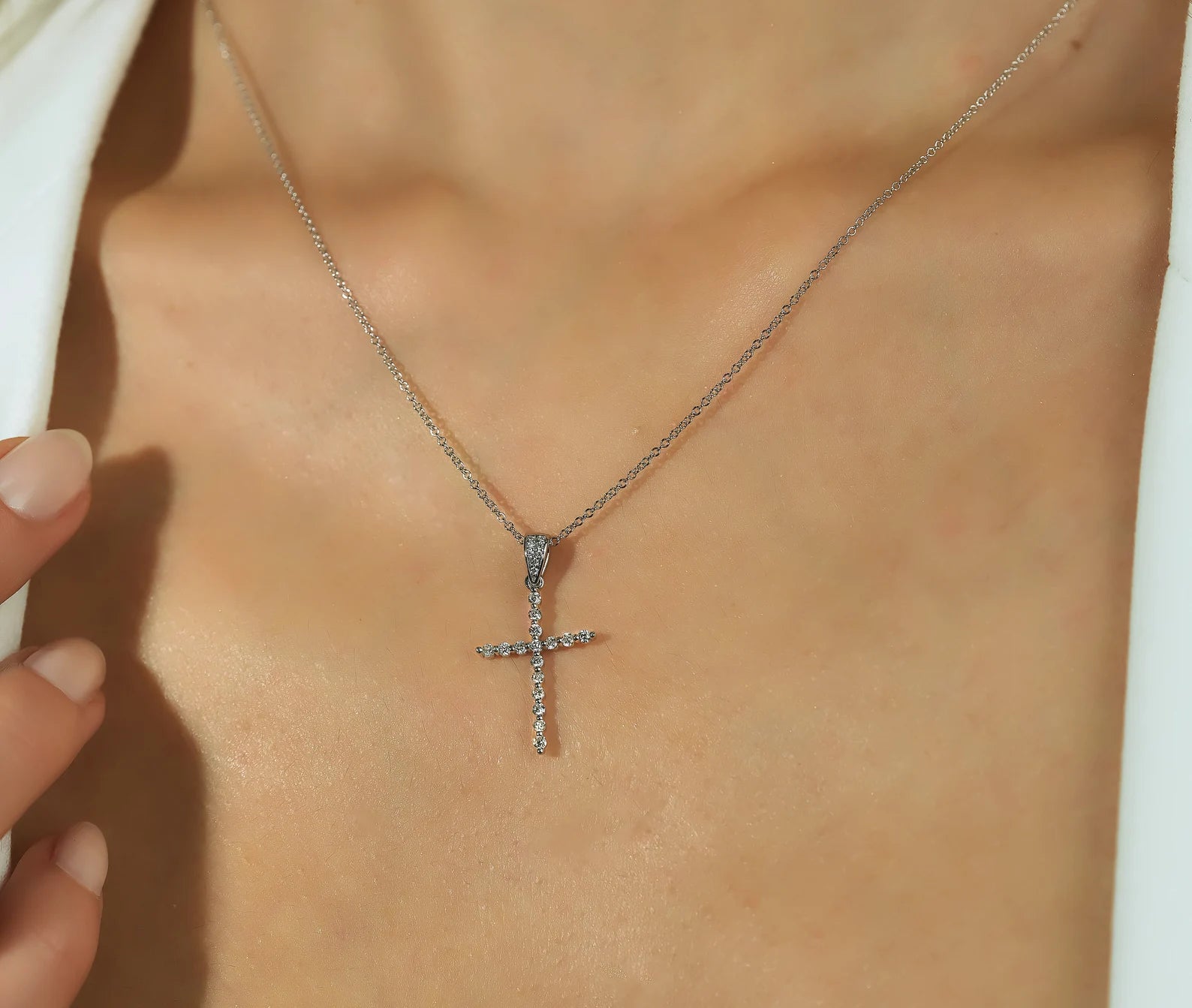 14K white gold minimalist diamond cross necklace worn on neck, featuring sparkly lab-created diamonds.