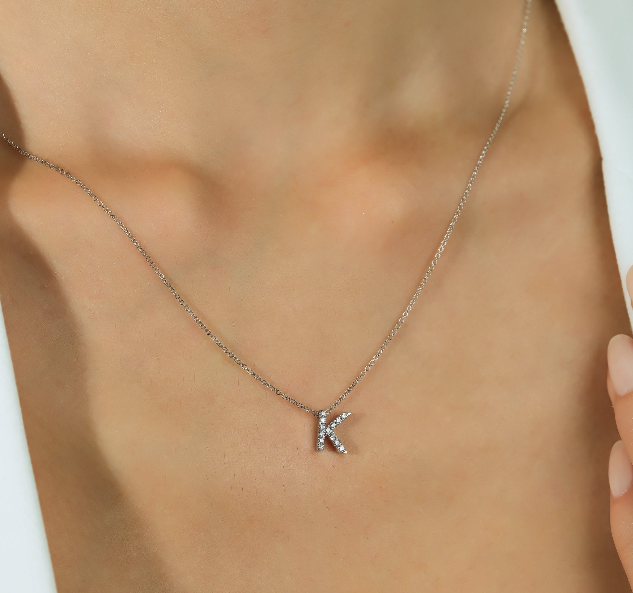 14K white gold diamond initial necklace featuring letter K, elegantly displayed on a model's neck.
